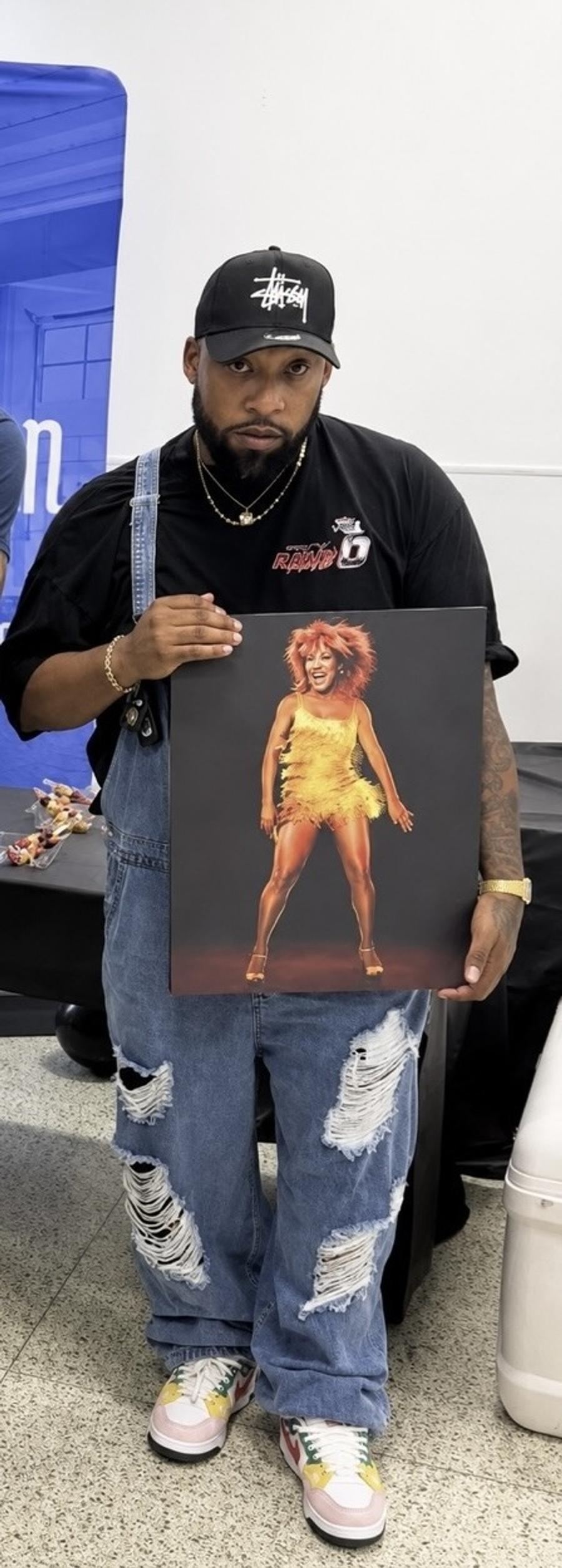 T Shocking holding Johnny Green's painting of Tina Turner performing in a gold fringe dress