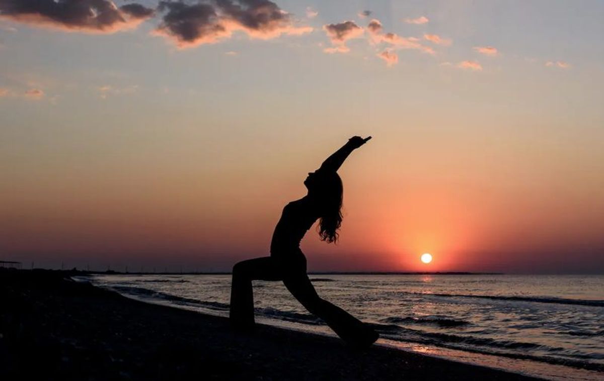 Silhouette of woman standing on dock during sunset