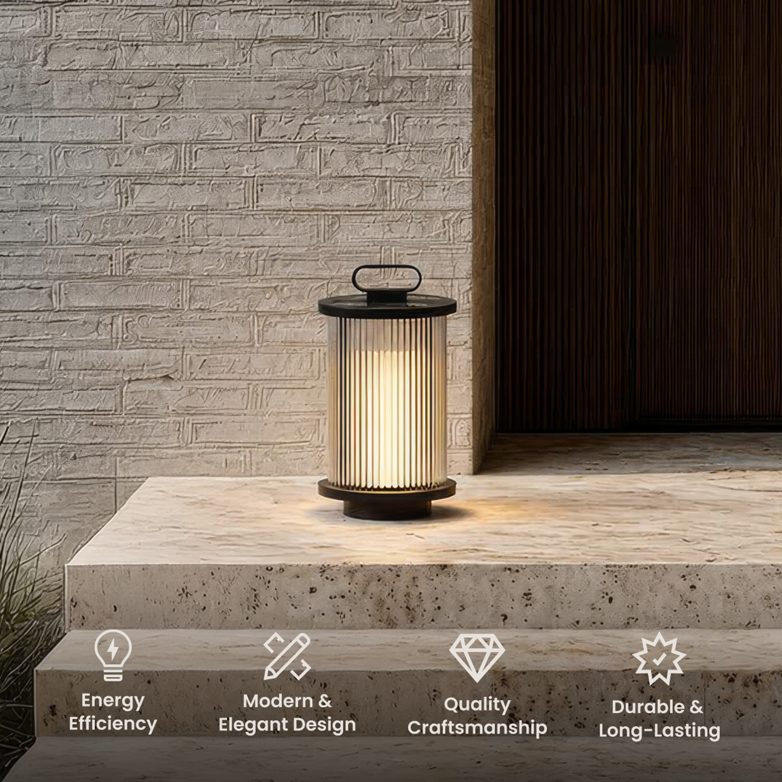Vesper black portable lantern, ribbed glass cylinder with a top handle, on a stone step by a brick wall