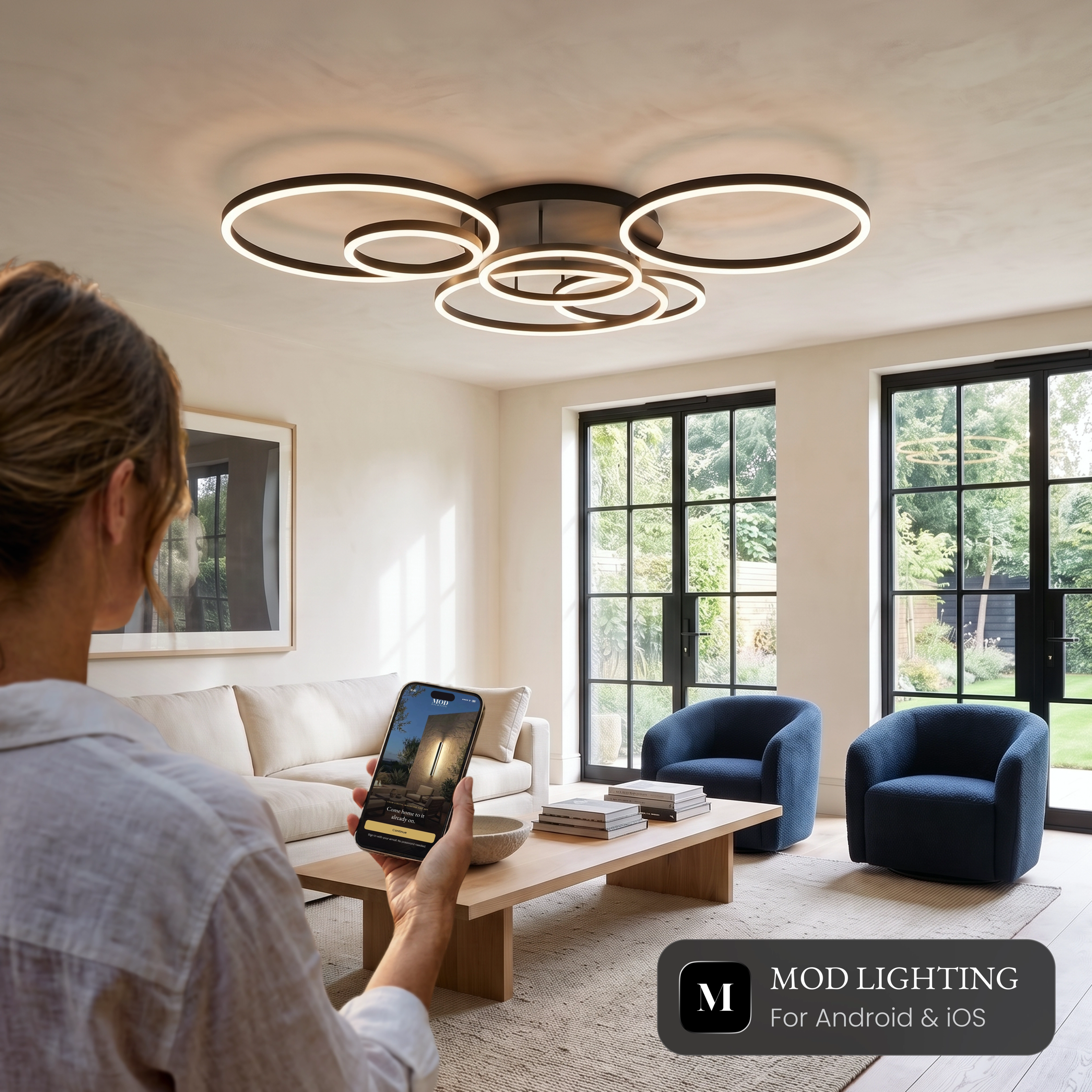 Woman controlling the black Chloe Smart ceiling light from the MOD Smart Home app on her phone