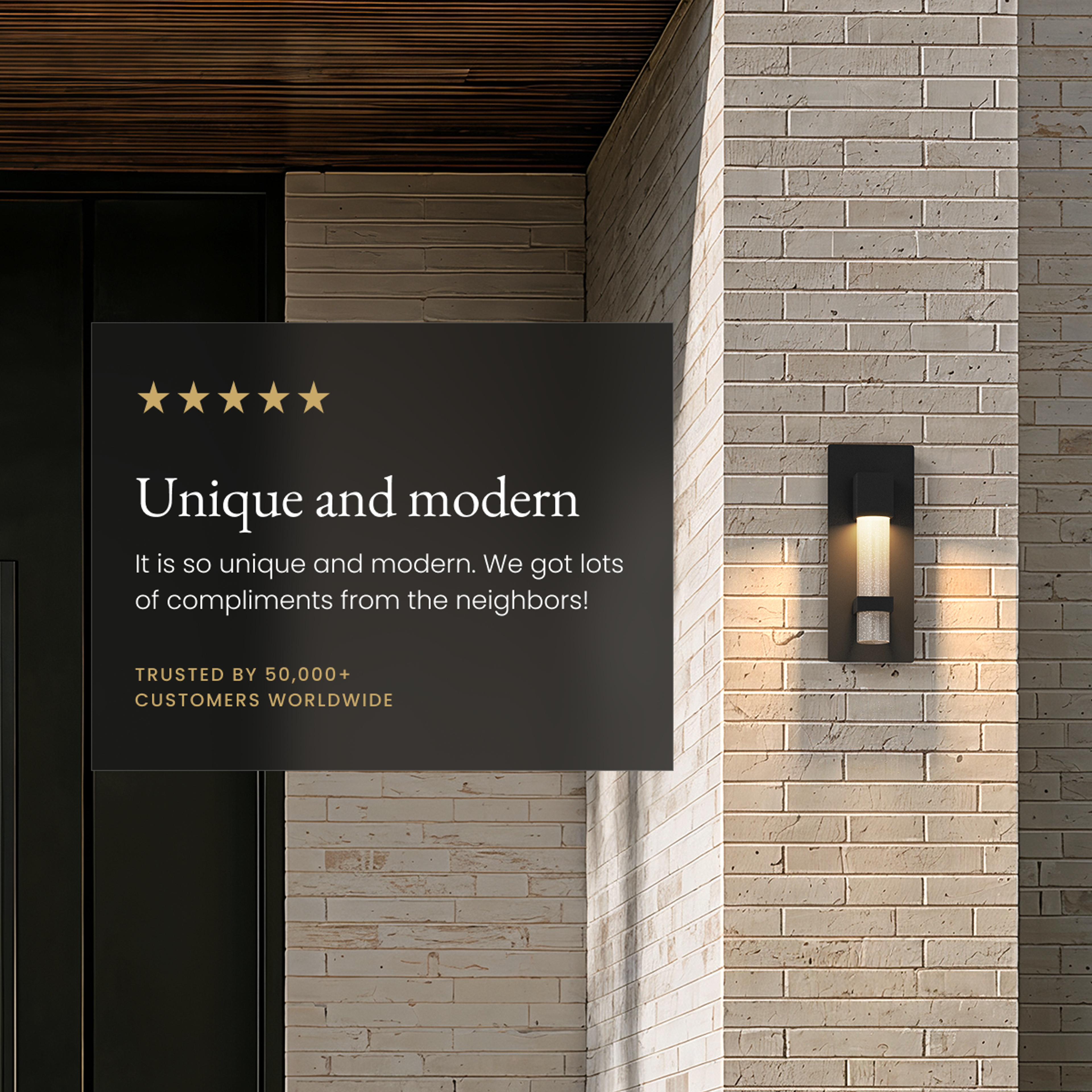 Astra black outdoor sconce, vertical seeded-crystal column glowing on a stone-brick facade beside a review card
