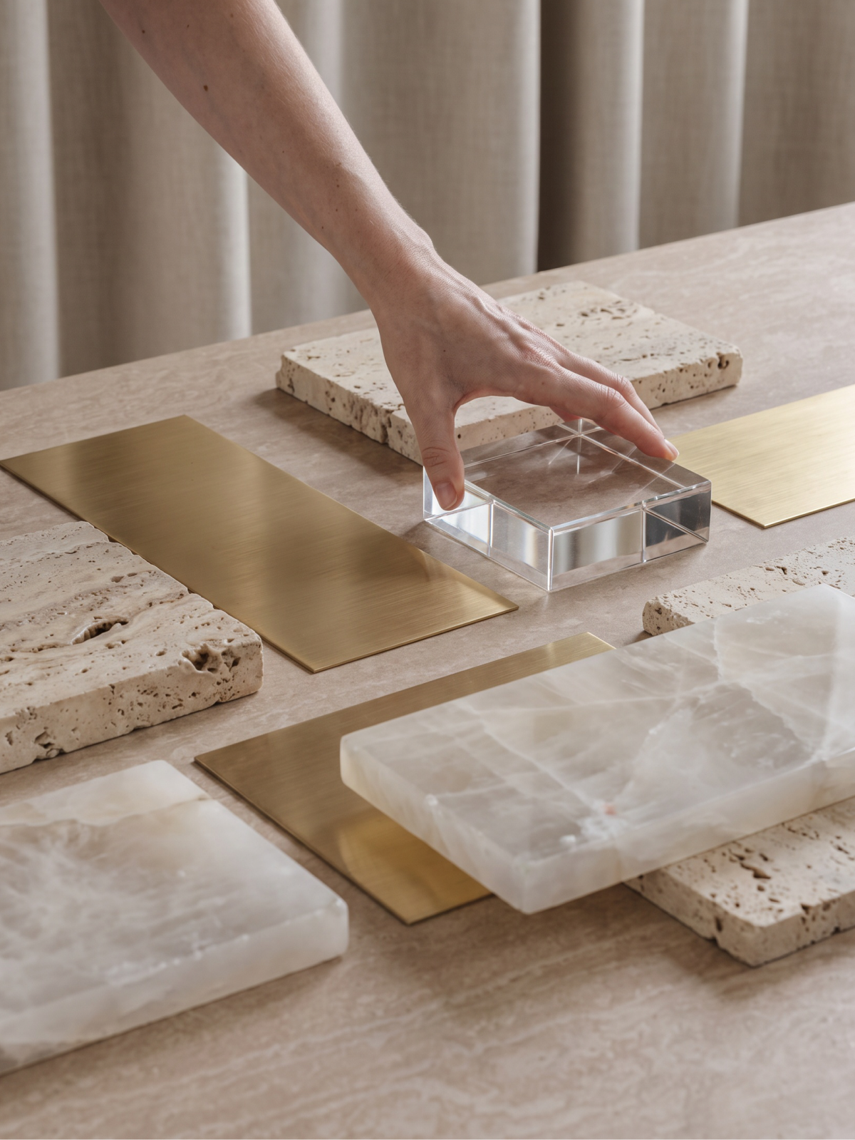 Hand placing brass and stone material samples on a travertine surface