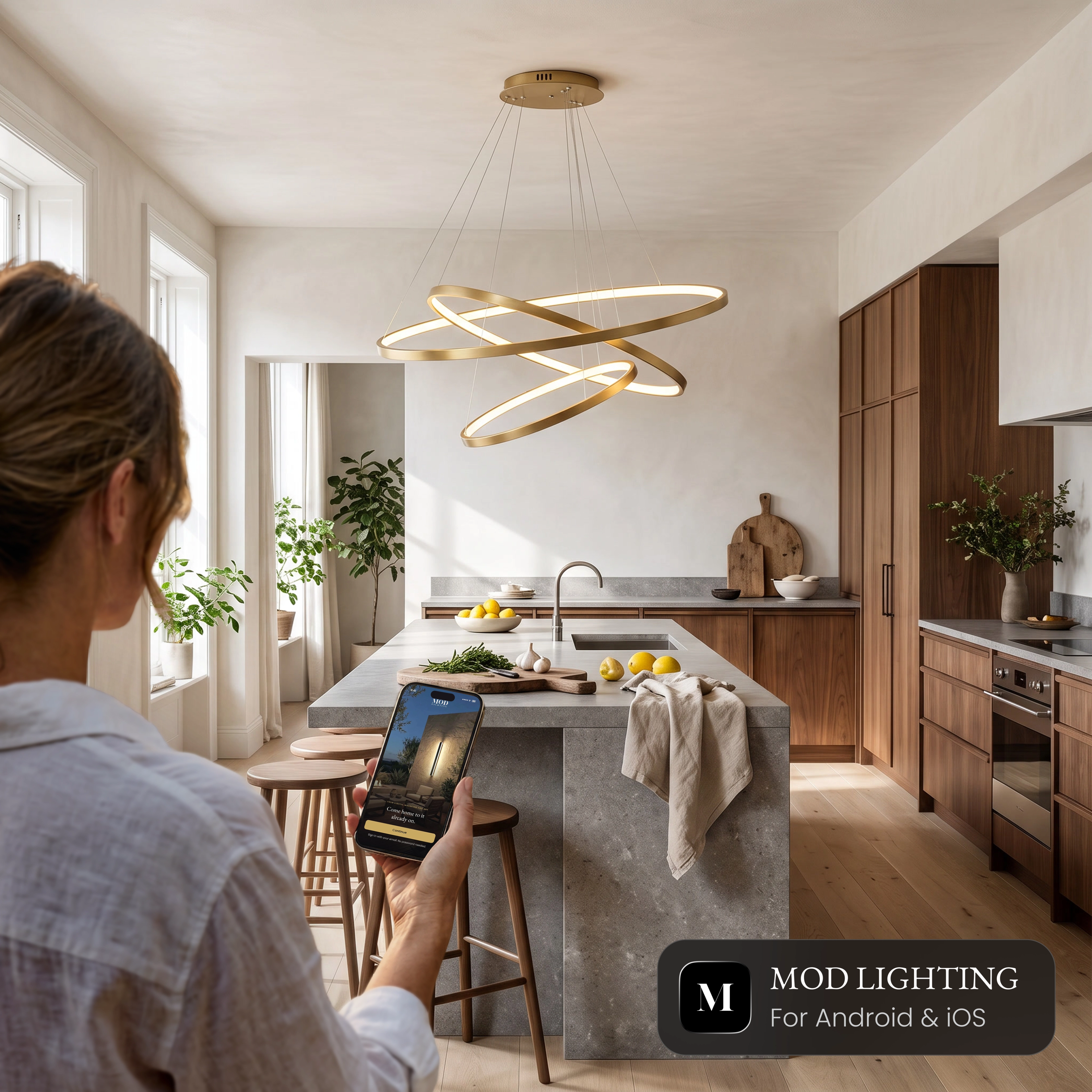 Janet Smart ring chandelier over a kitchen island, controlled from the MOD LIGHTING app on a phone