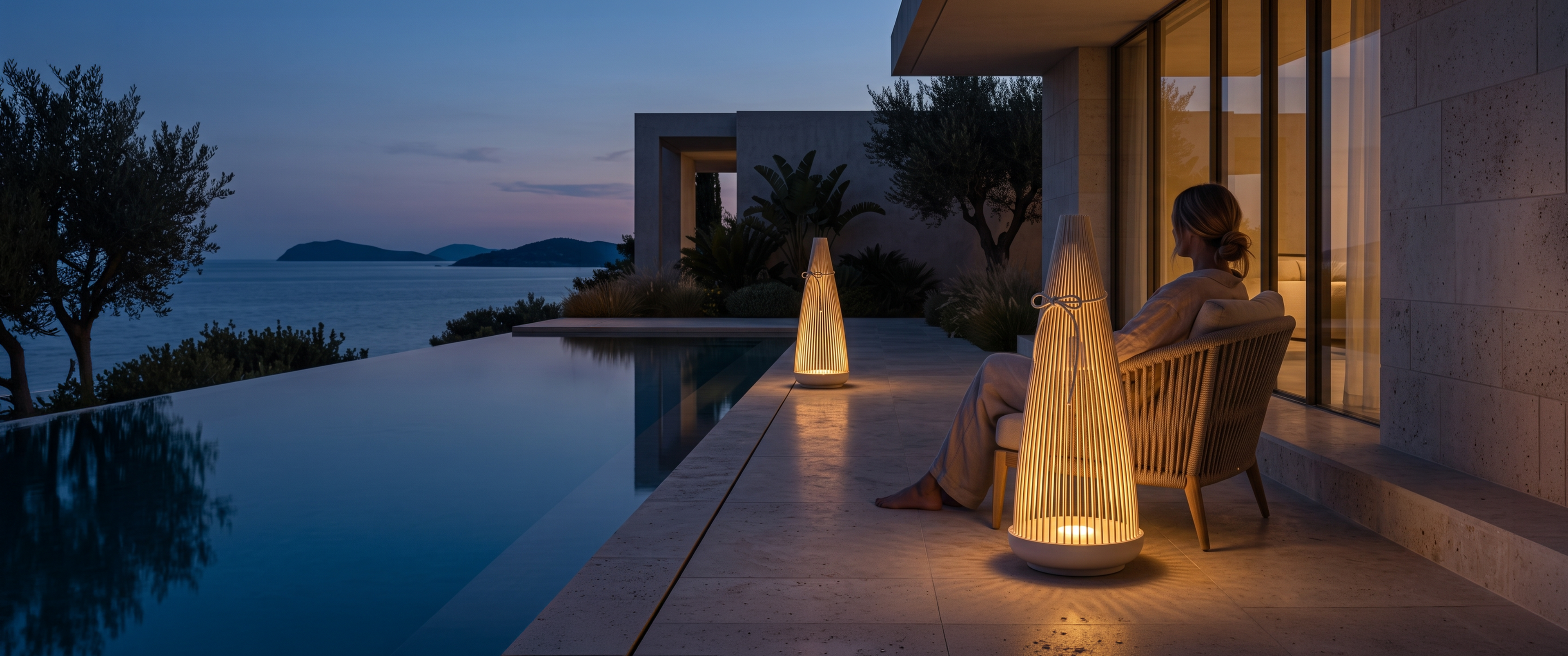 Two woven outdoor lanterns lit at dusk beside a pool