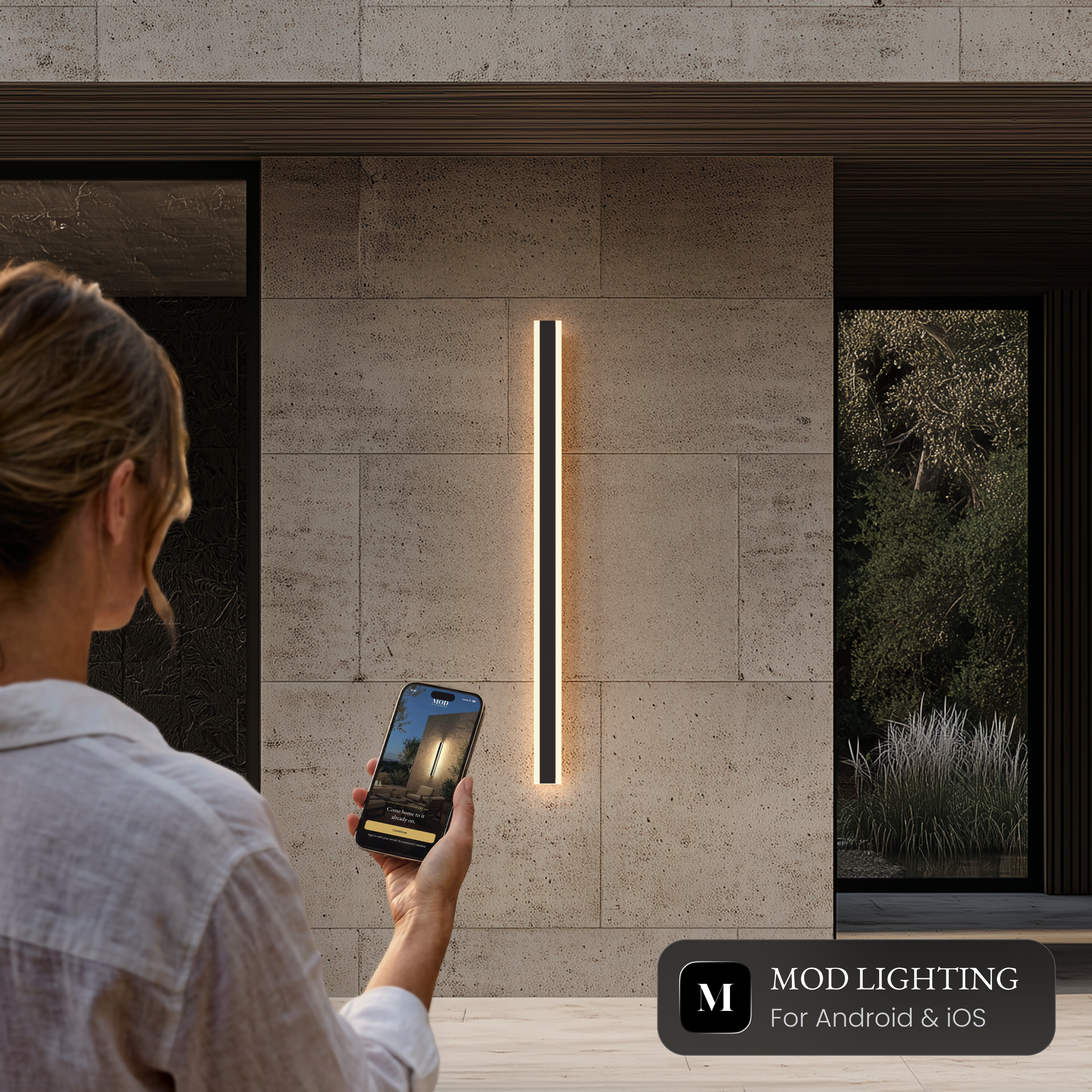 Haylen slim black LED bar light on a stone exterior wall, controlled from a smartphone app