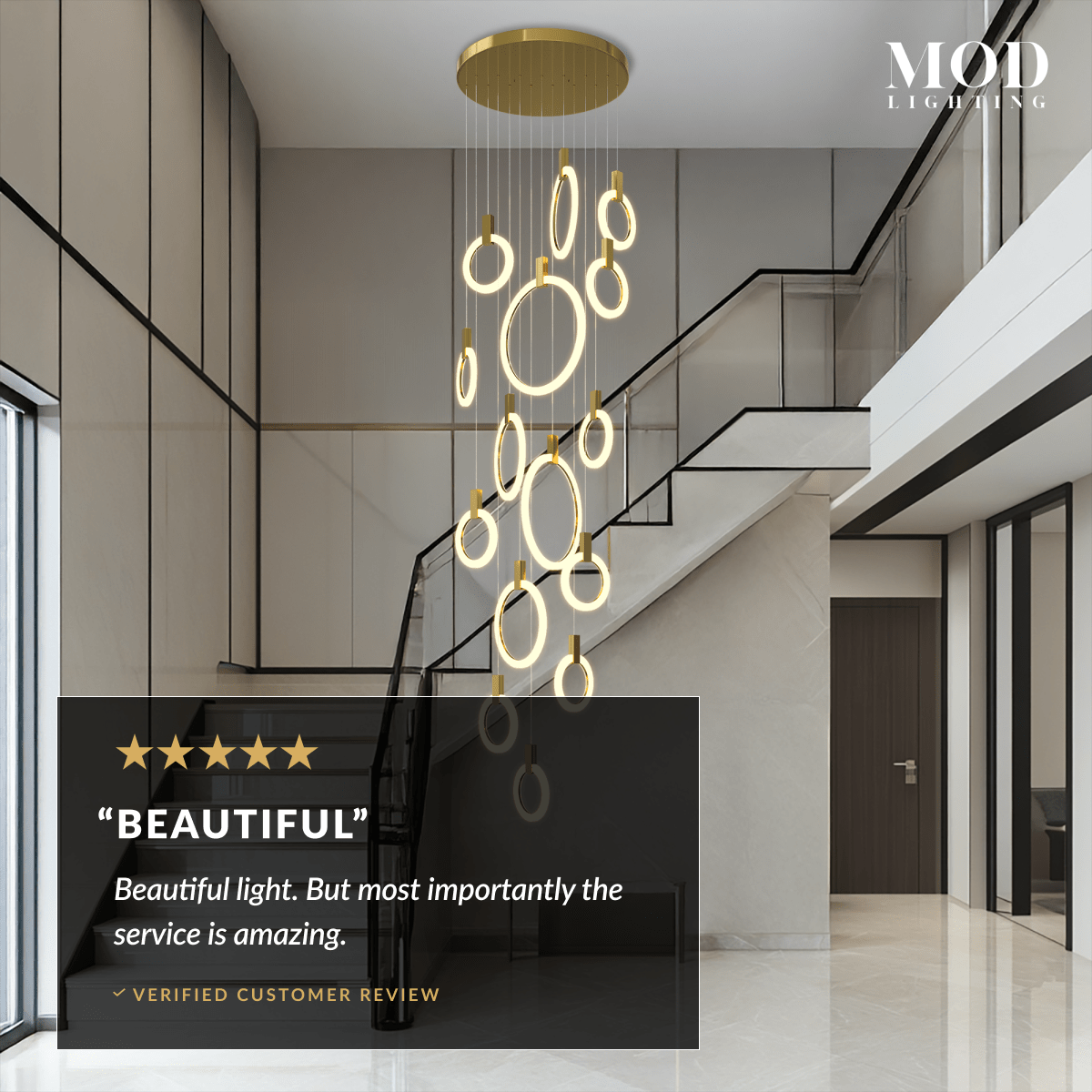 Skyla chandelier in gold, staggered lit rings cascading down a two-story staircase entryway