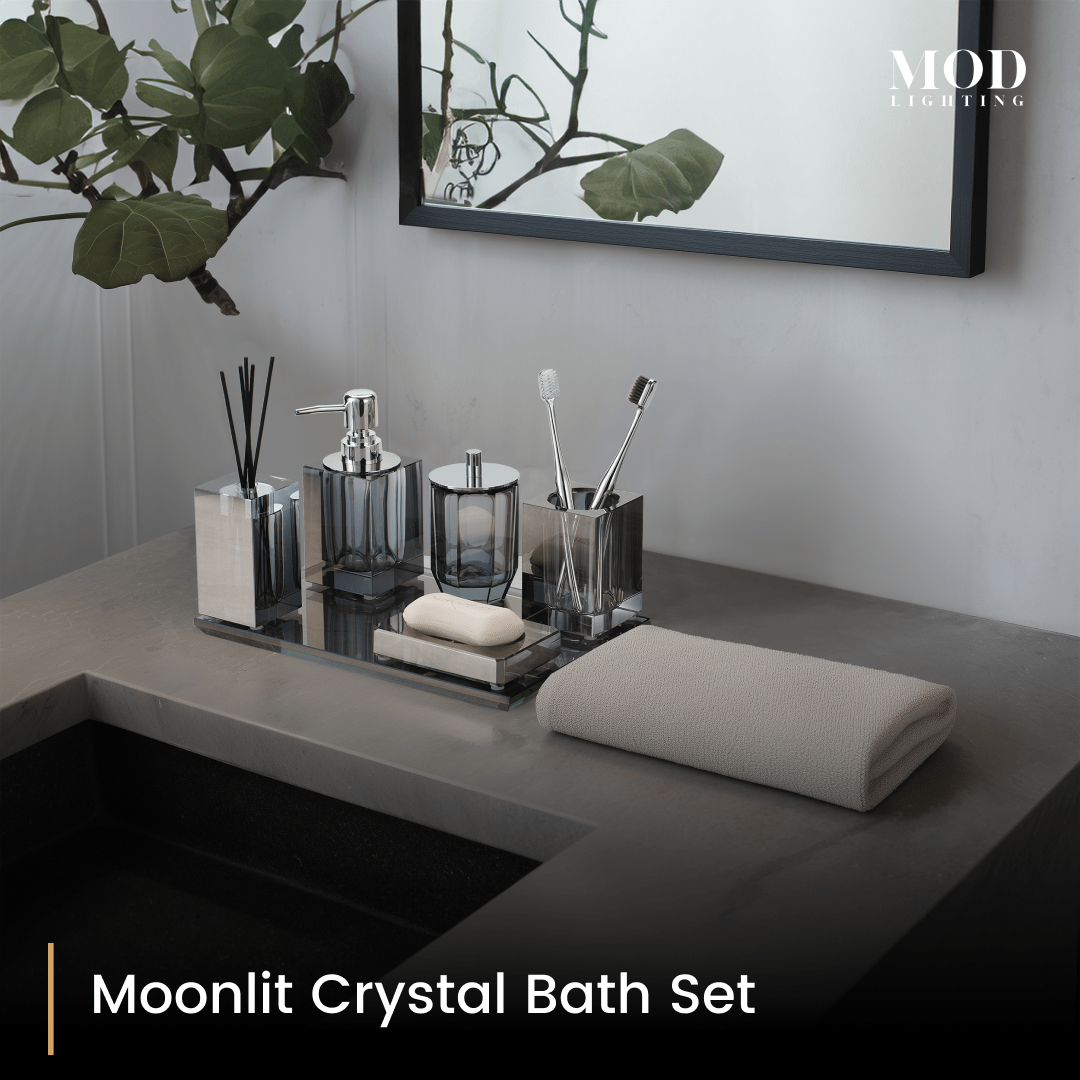Moonlit Crystal Bath Set, smoky grey crystal accessories on a mirrored tray on a dark vanity beside a round mirror