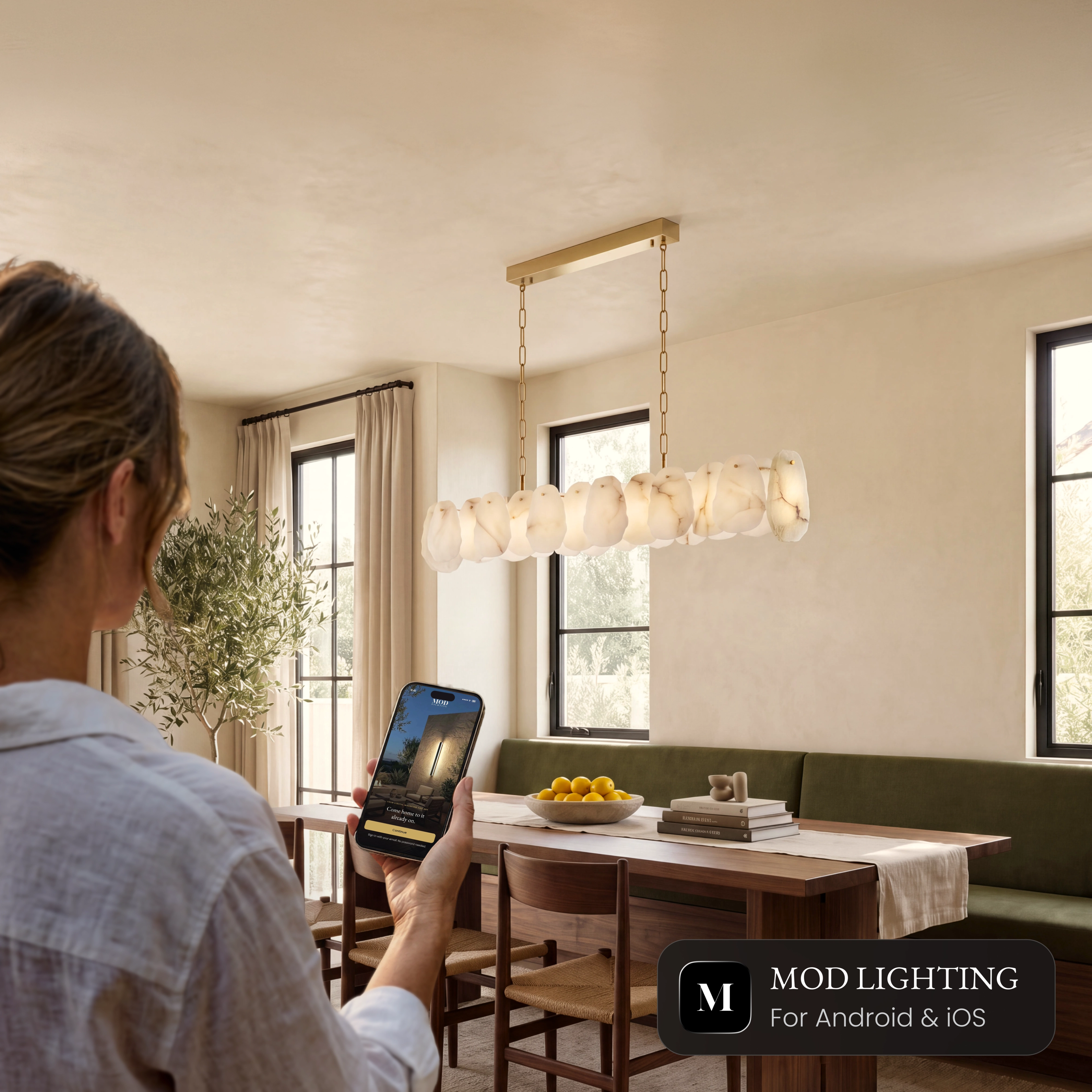 Alba Pendant Smart linear alabaster pendant over a dining table, controlled from the MOD LIGHTING app on a phone