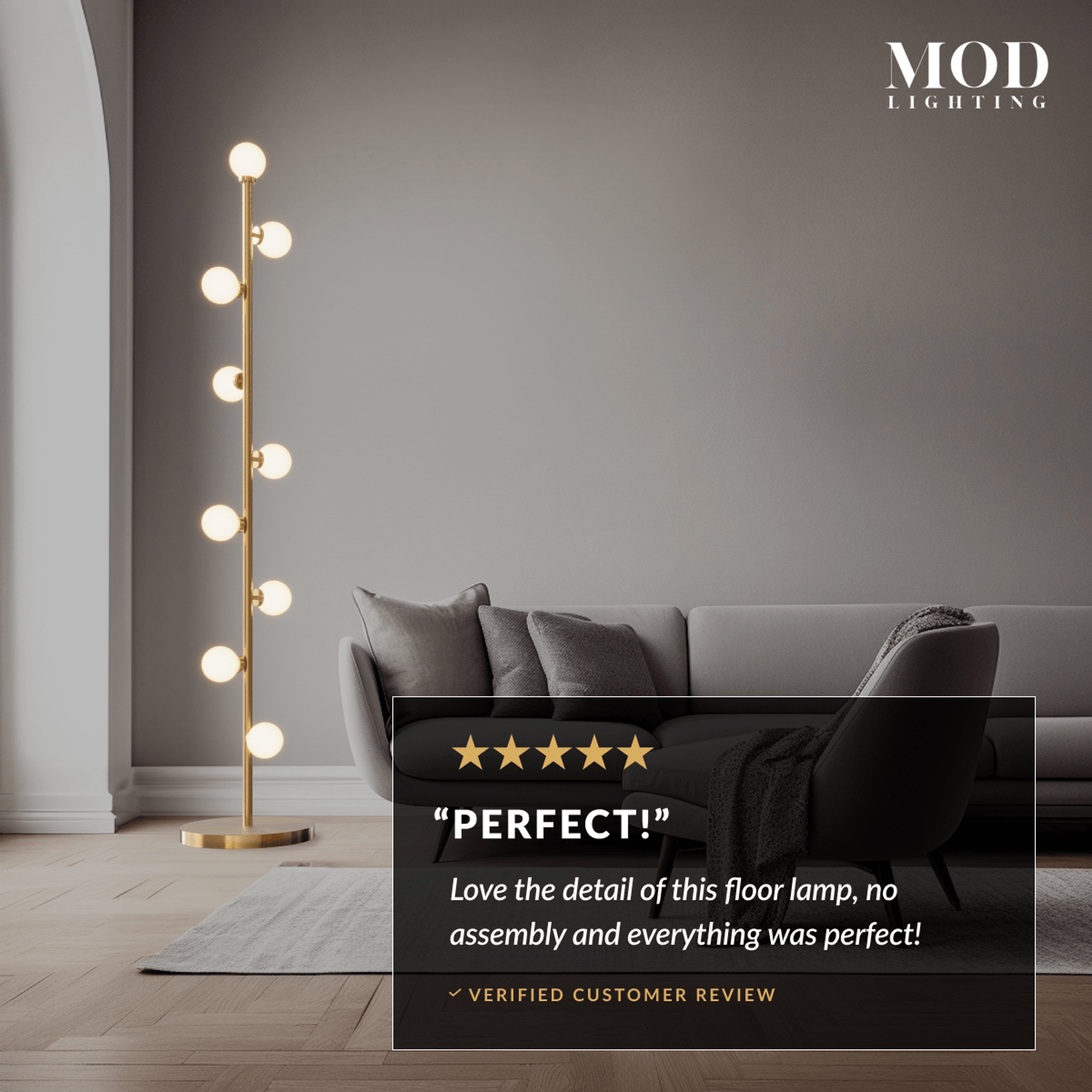 Pearl floor lamp lit in a dark living room, gold stem with glowing frosted glass globes beside a sofa