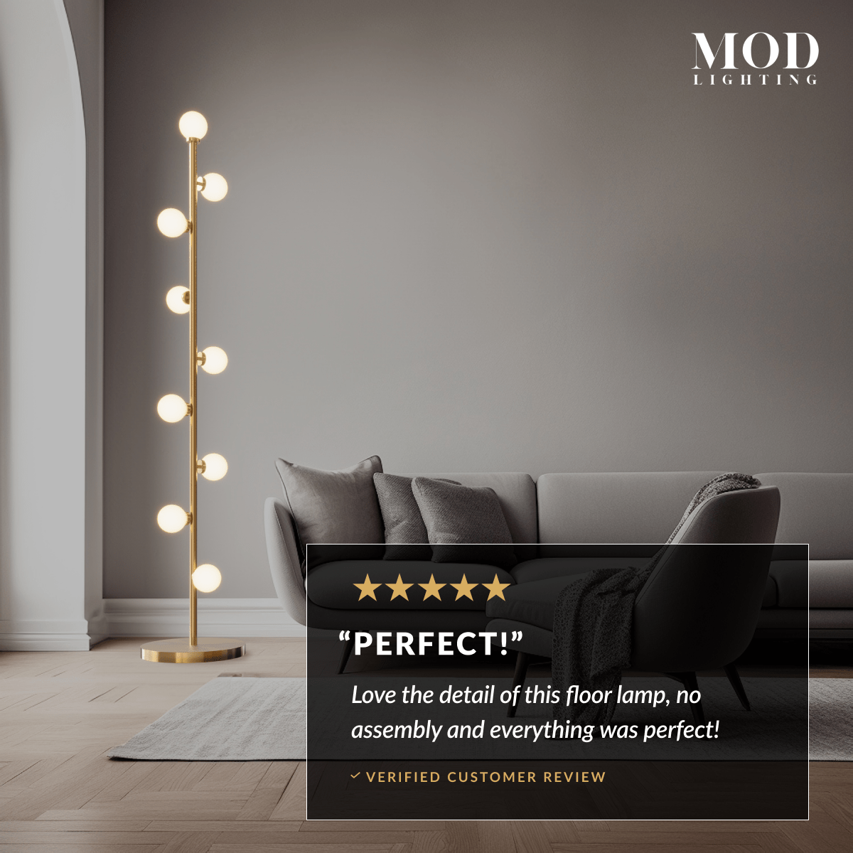 Pearl floor lamp lit in a dark living room, gold stem with glowing frosted glass globes beside a sofa