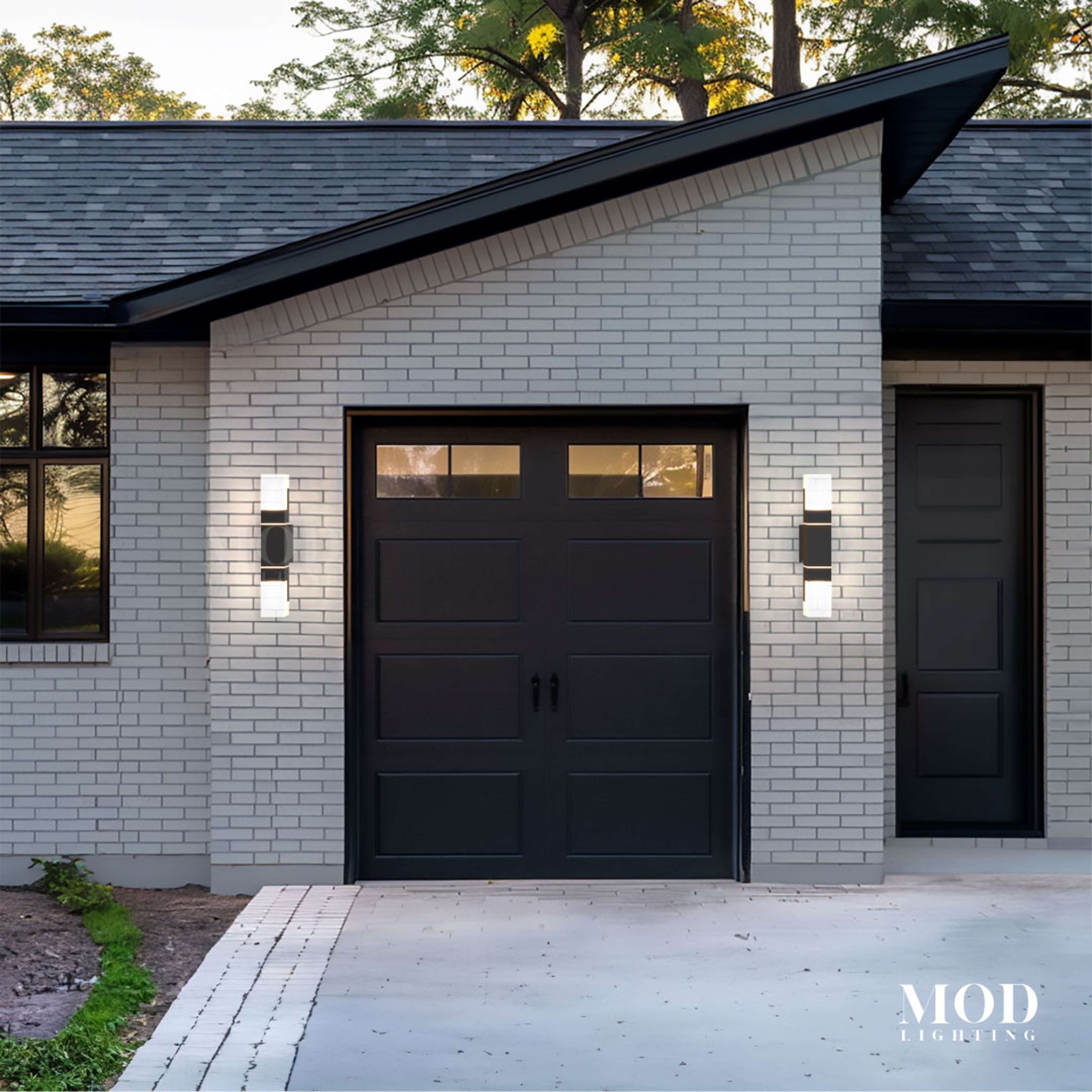 Falcon black outdoor sconces, slim dual-glow bars flanking a garage door on white brick facade