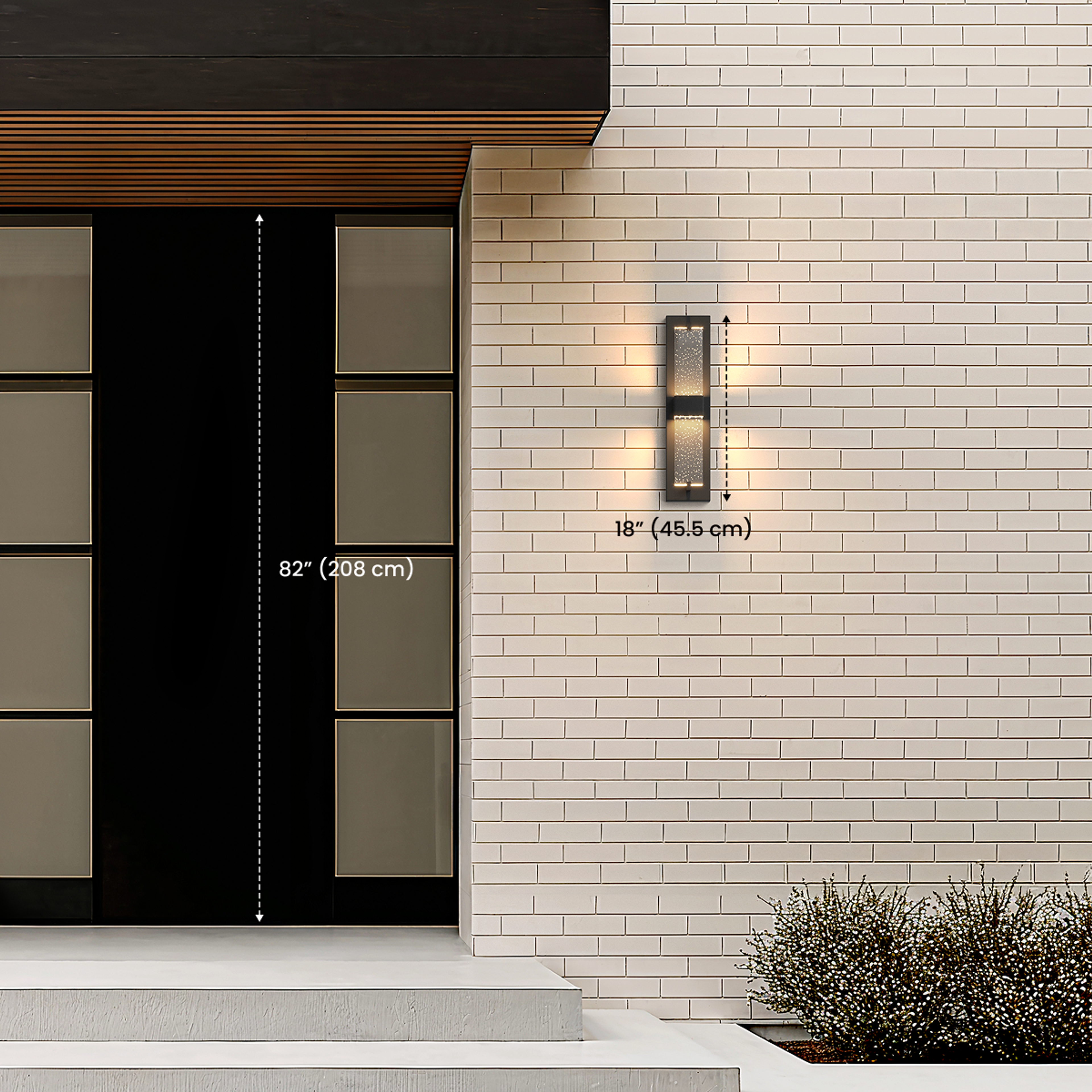 Noir black outdoor sconce mounted by a dark entry door, dimension diagram noting 32.7 in / 83 cm height and 18 in / 45.5 cm