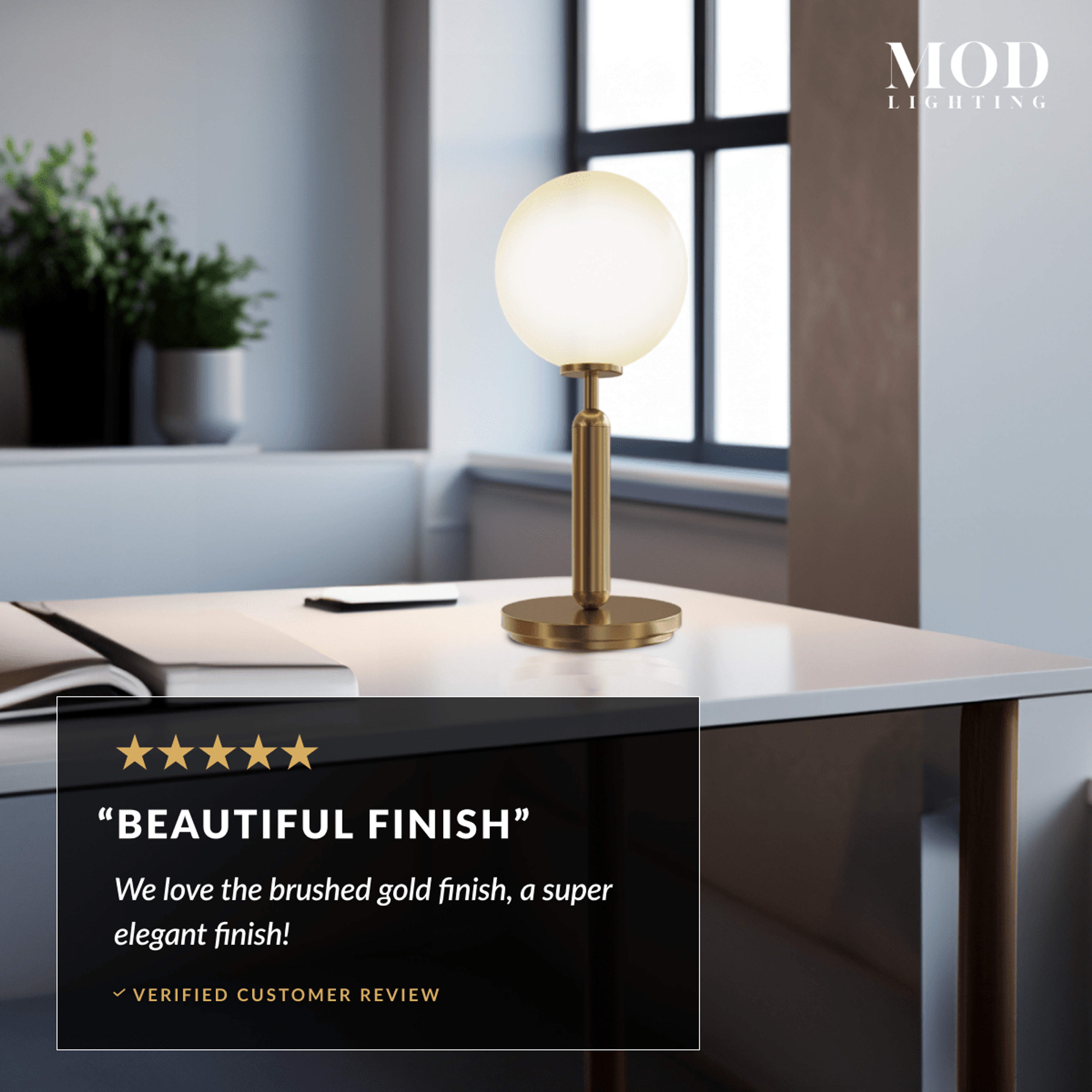 Angelica gold table lamp, white opal-glass globe on a brushed-brass stem and base, on a desk by a window