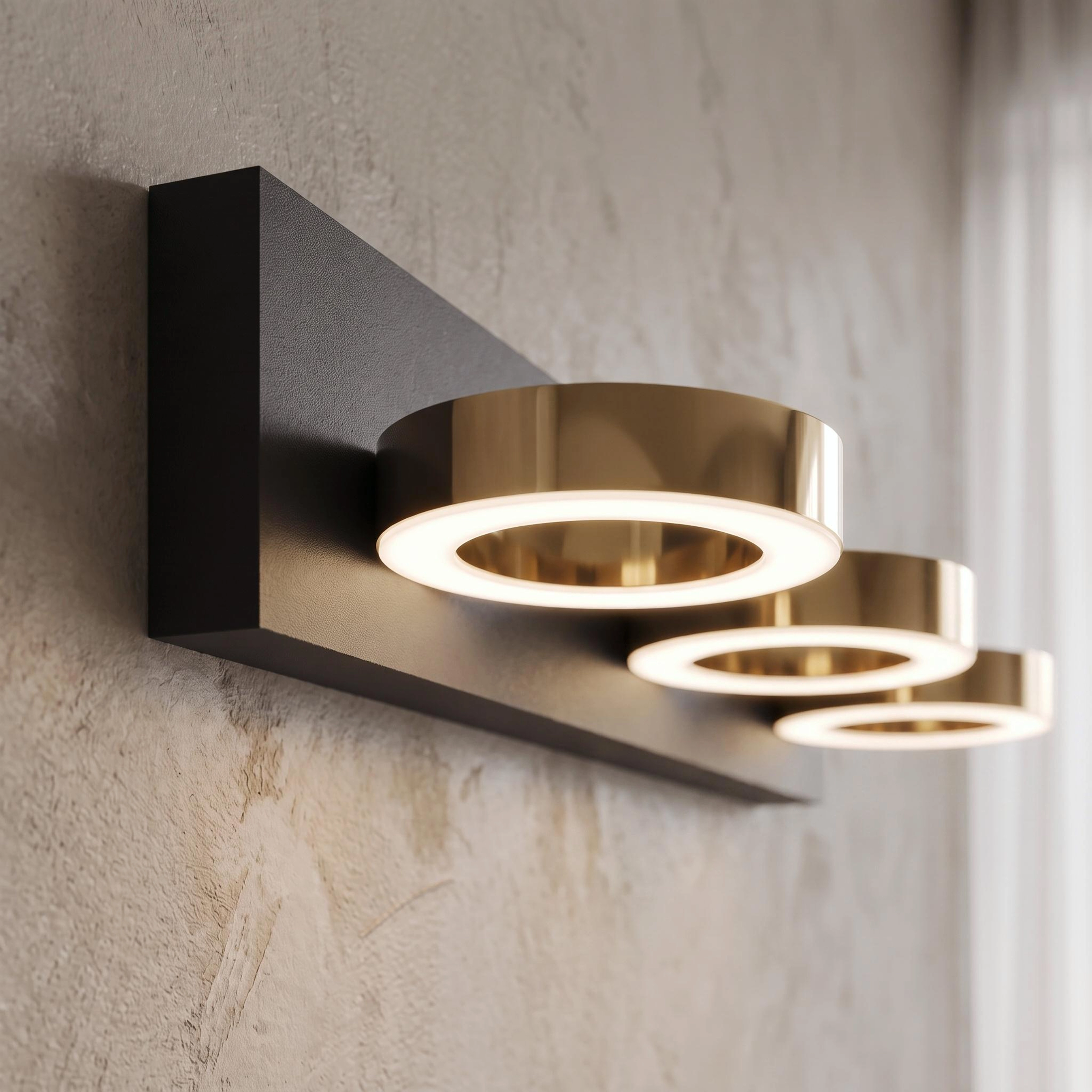 Aurora black three-light bathroom fixtures with gold rings over twin mirrors in a marble bathroom, warm white 3000K