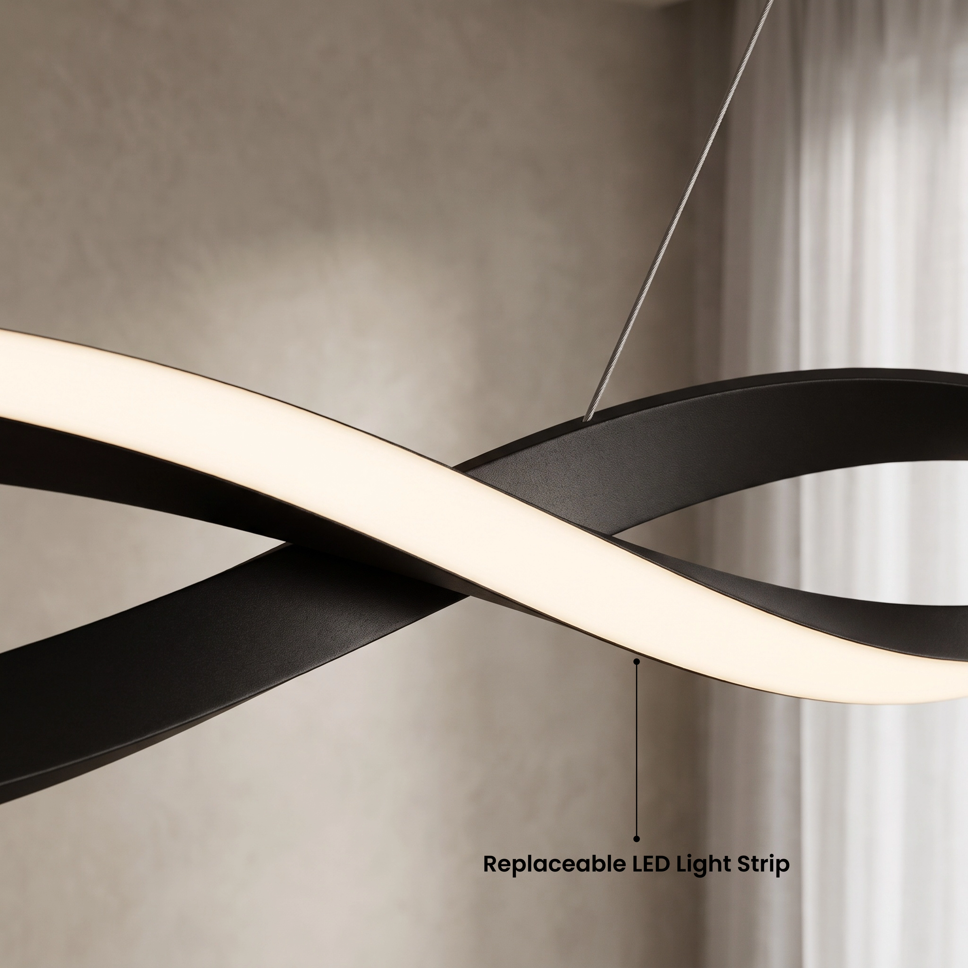 Wavey pendant, black twisted ribbon with warm-white LED, above a dark sofa; available in three sizes