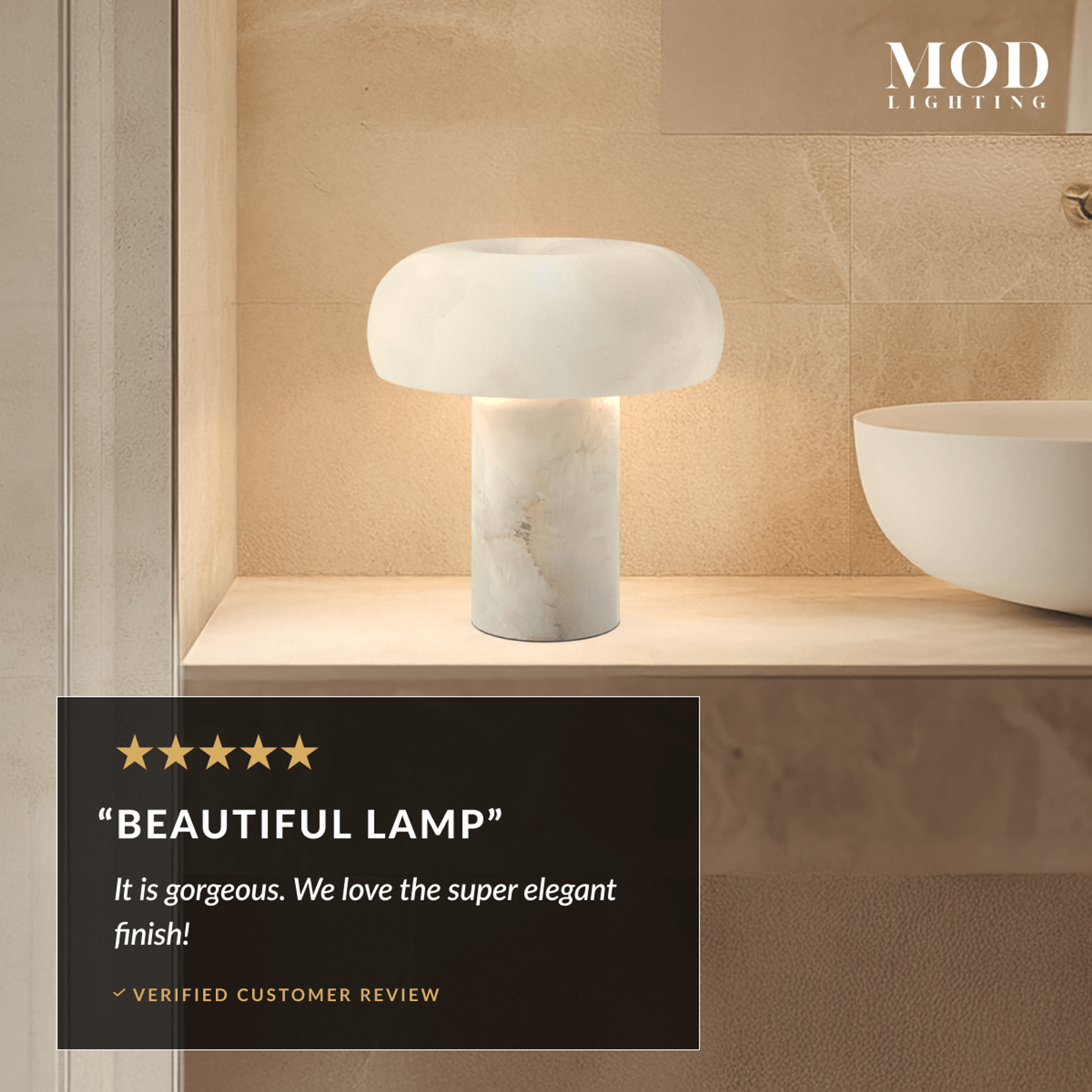 Ora Table Lamp, domed alabaster shade on a cylindrical stone base, lit on a bathroom shelf beside a basin