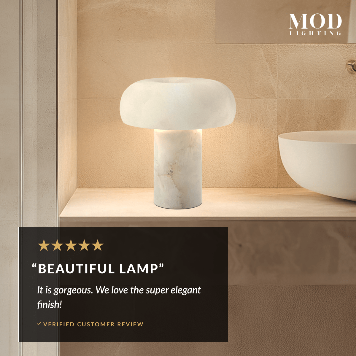 Ora Table Lamp, domed alabaster shade on a cylindrical stone base, lit on a bathroom shelf beside a basin