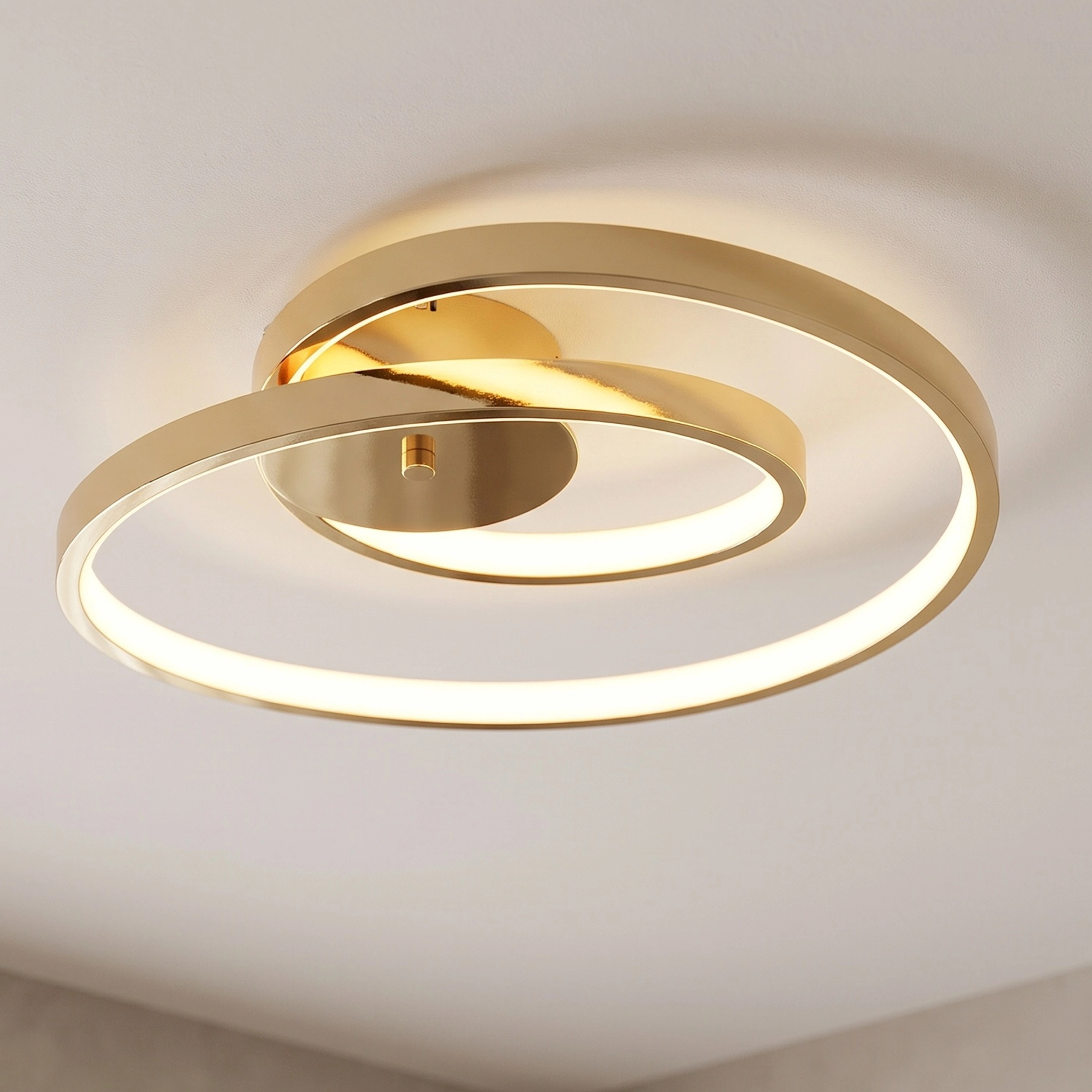 Elise gold spiral-ring flush-mount ceiling light in a living room, warm white 3000K, two sizes