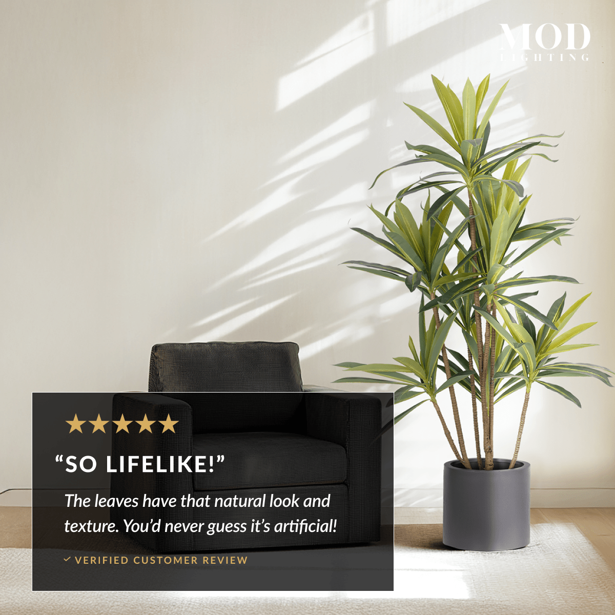 Dracaena artificial plant in a grey pot beside an armchair, with a five-star "So lifelike!" customer review overlay