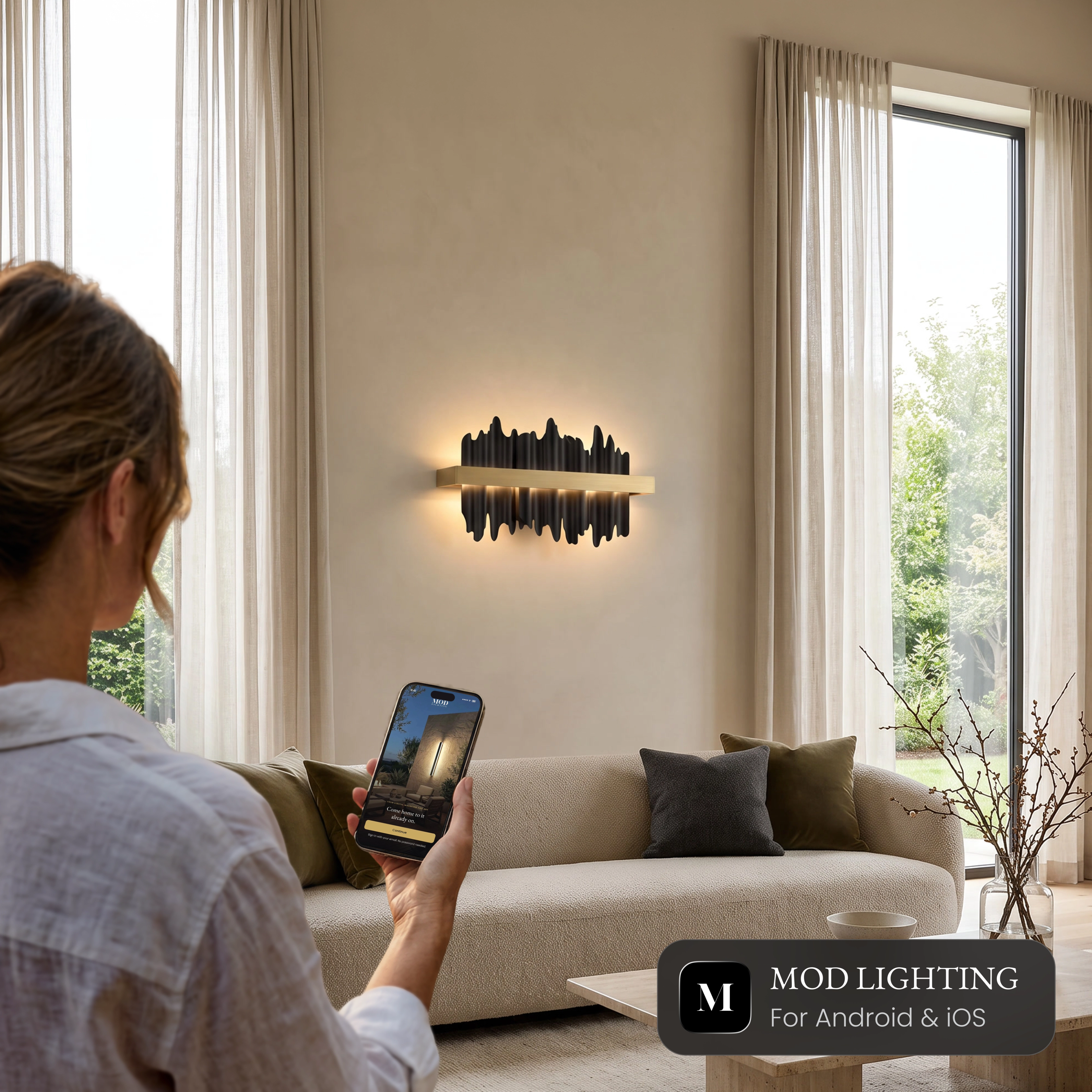 Woman controlling the Aurelius Sconce Smart wall light from the MOD LIGHTING app on her phone
