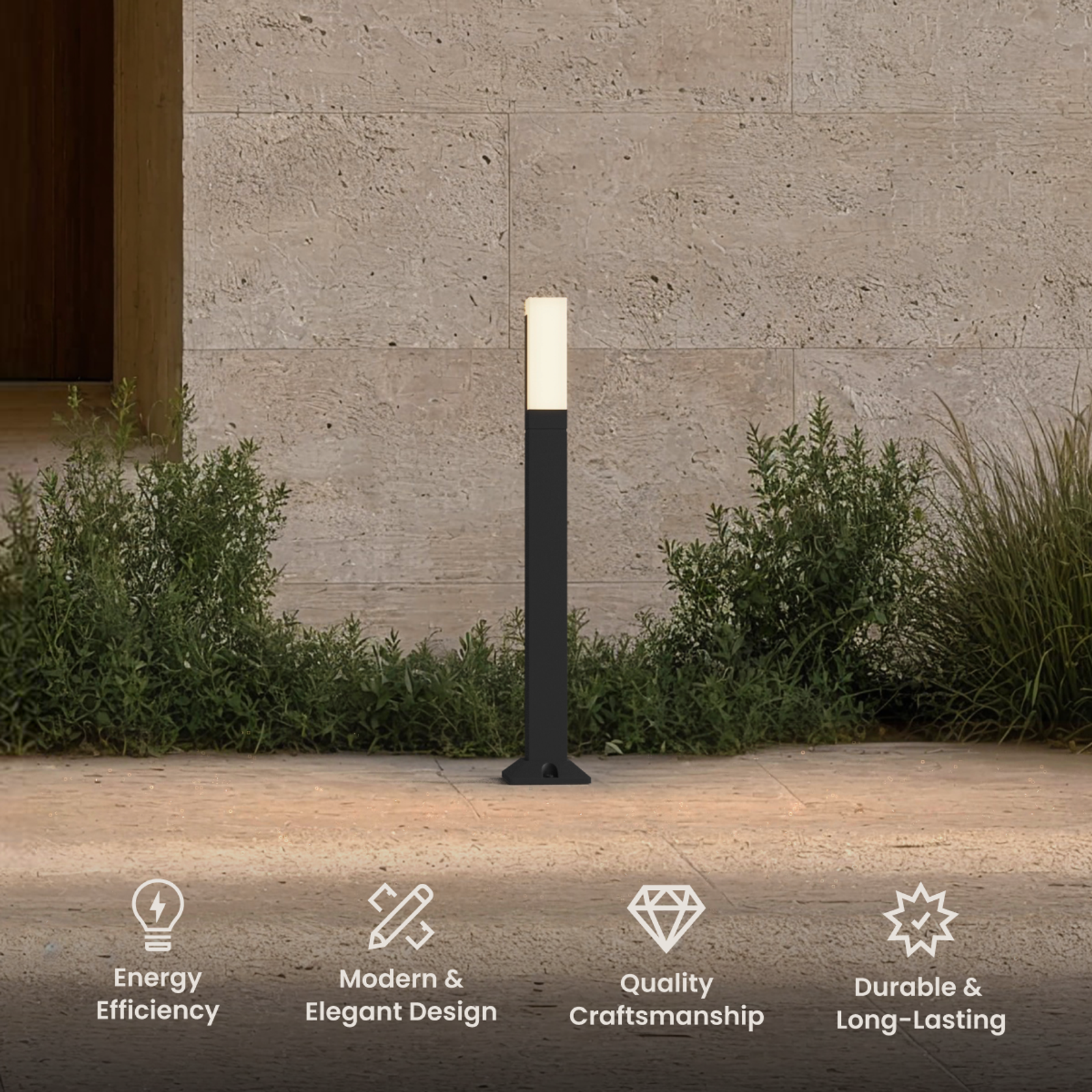 Meadow outdoor bollard, slim black post with lit frosted top, standing in a garden bed by a stone wall