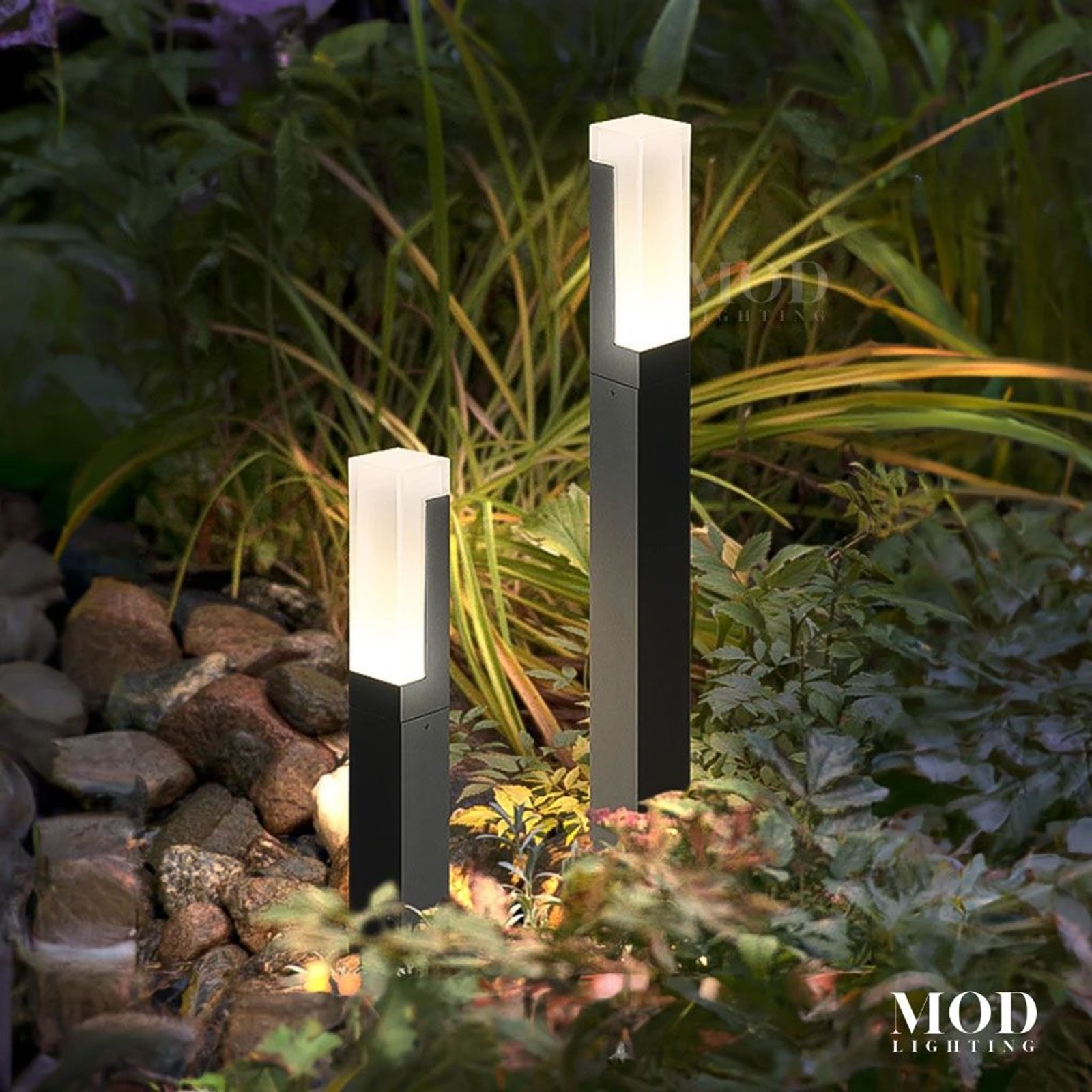 Meadow two black outdoor bollard path lights with frosted glowing tops among garden plants
