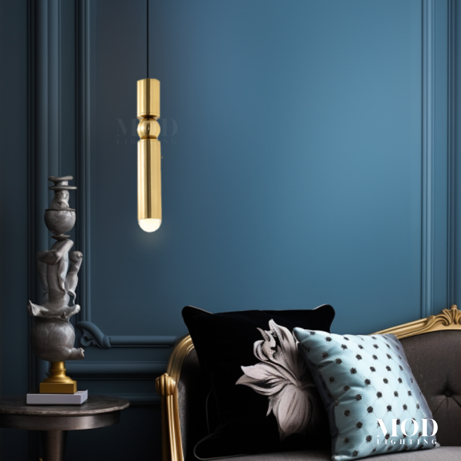 Jetta, single slim gold cylinder pendant against a deep blue wall beside a sofa