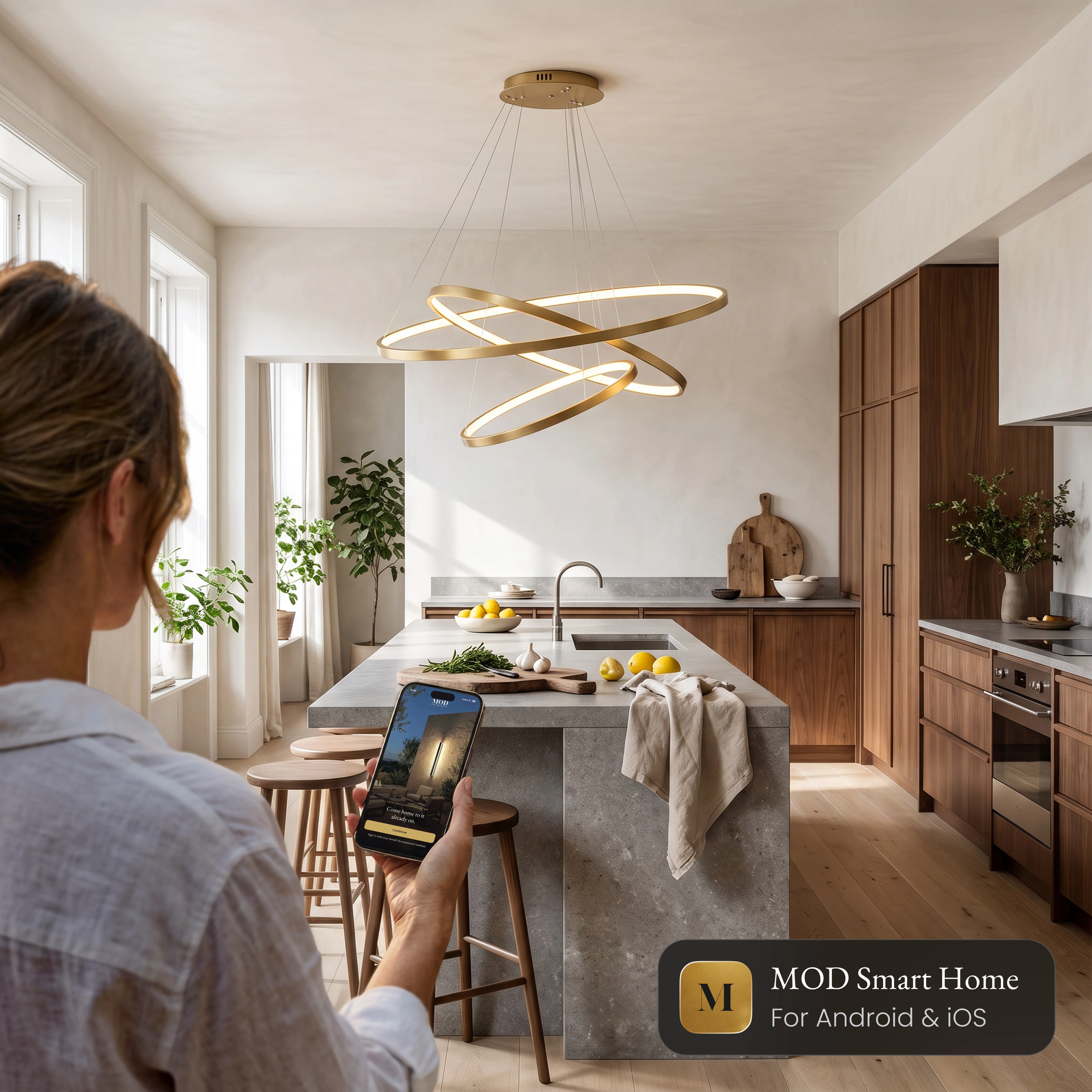 Janet Smart ring chandelier over a kitchen island, controlled from the MOD Smart Home app on a phone