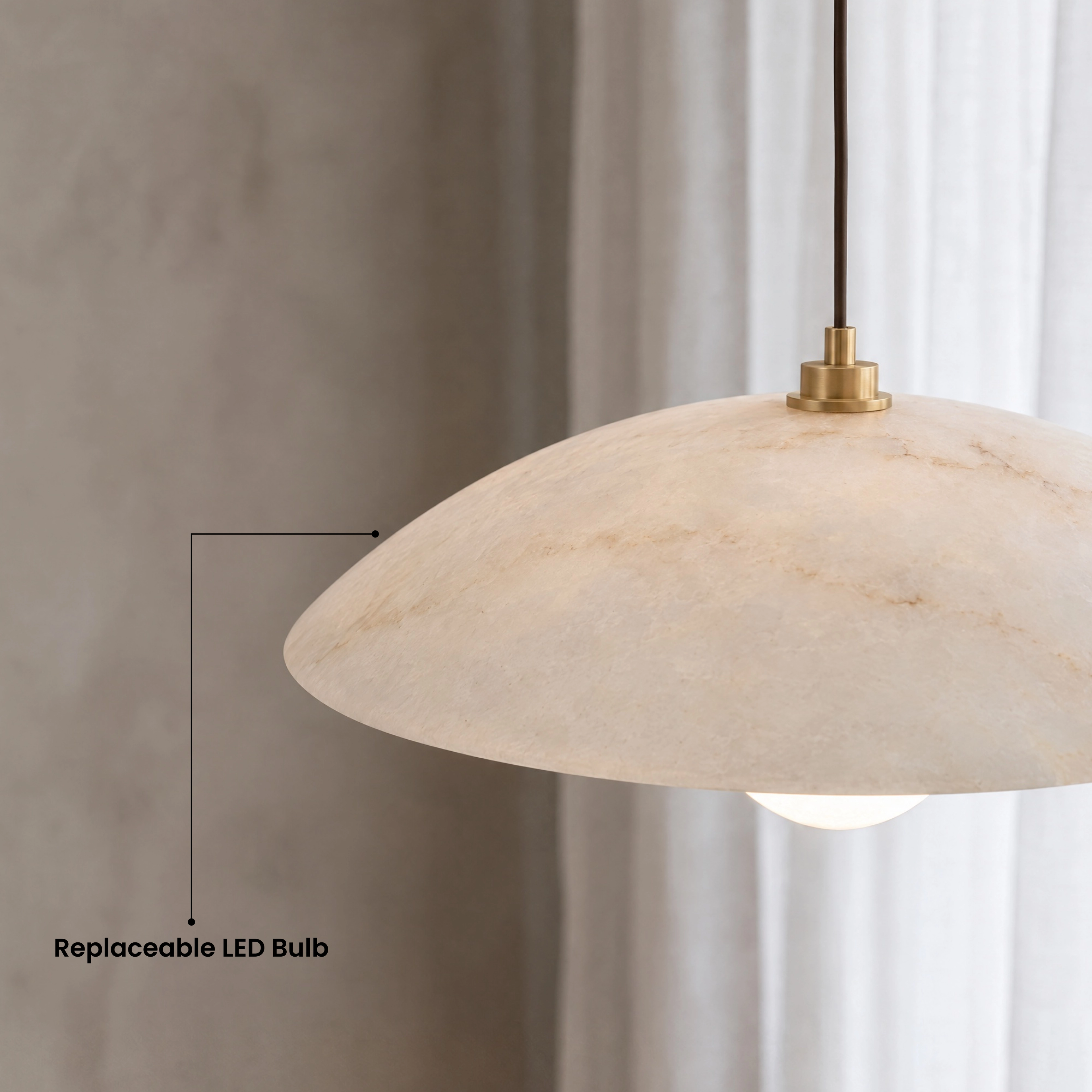 Zira alabaster dome pendant glowing warm white over a beige sofa in a paneled living room
