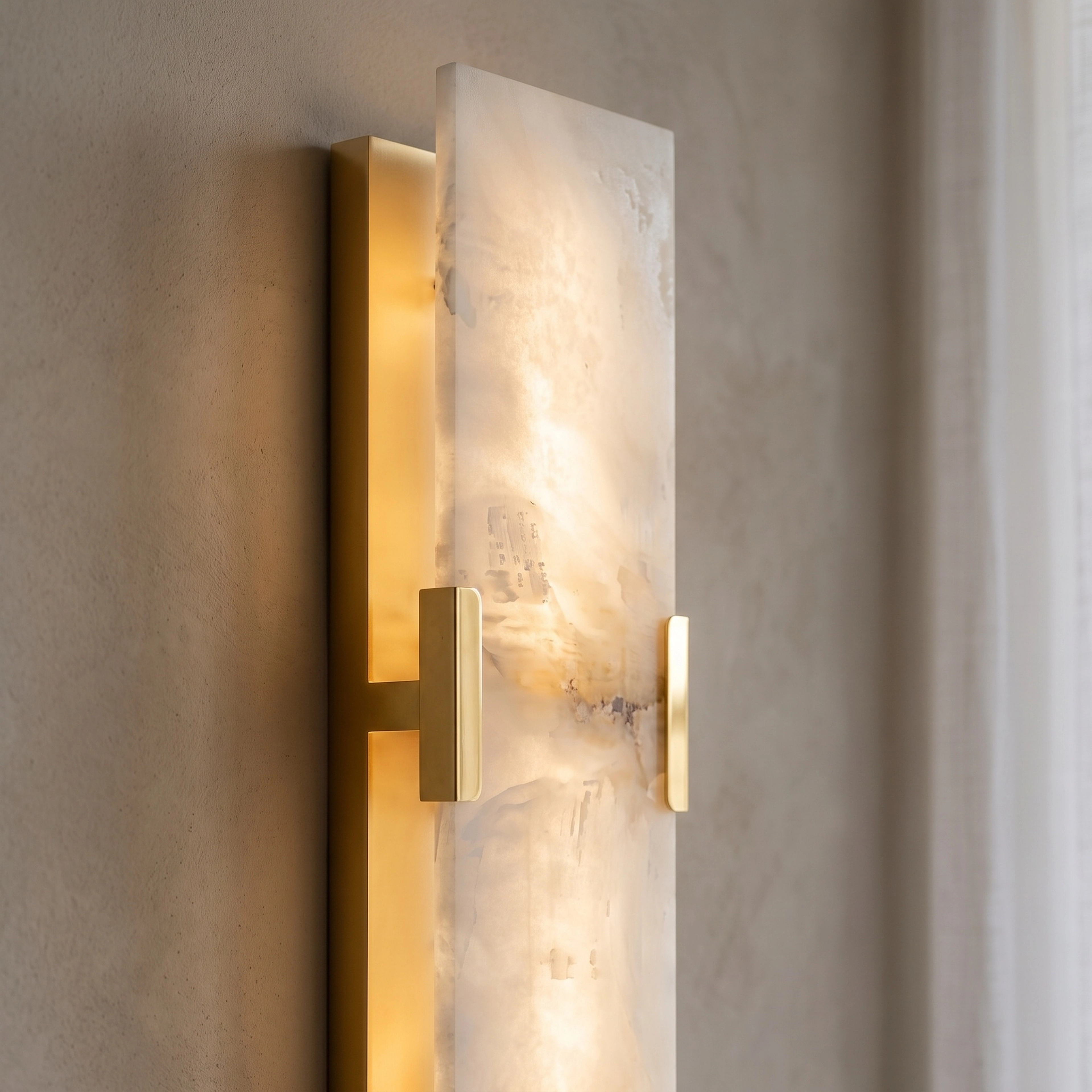 Rhea faceted alabaster wall sconces flanking a bed with a marble headboard wall in a warm bedroom