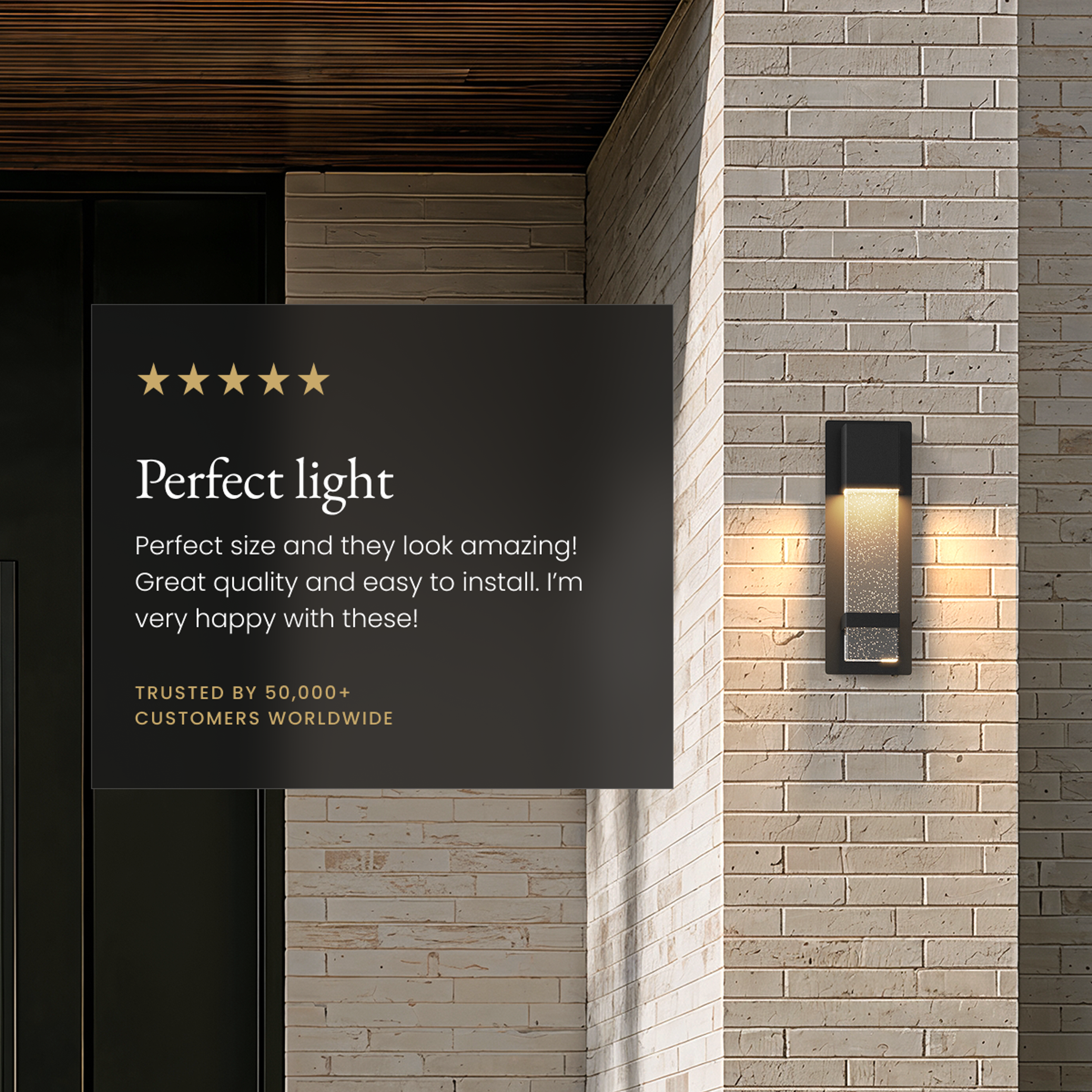 Nova black outdoor sconce, bubble-glass column glowing on a stone-brick facade beside a five-star review card