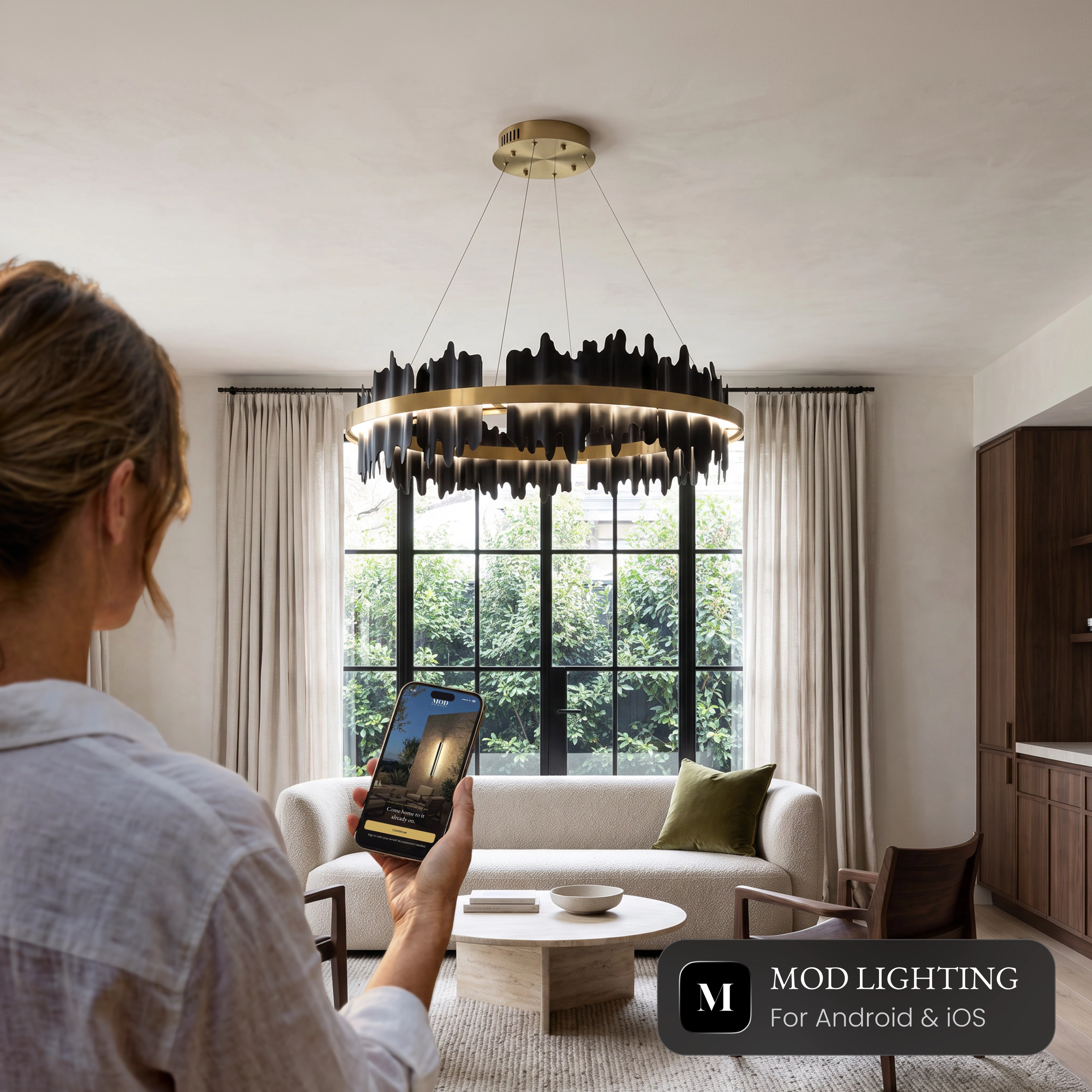 Woman controlling the Aurelius Smart chandelier from the MOD LIGHTING app on her phone