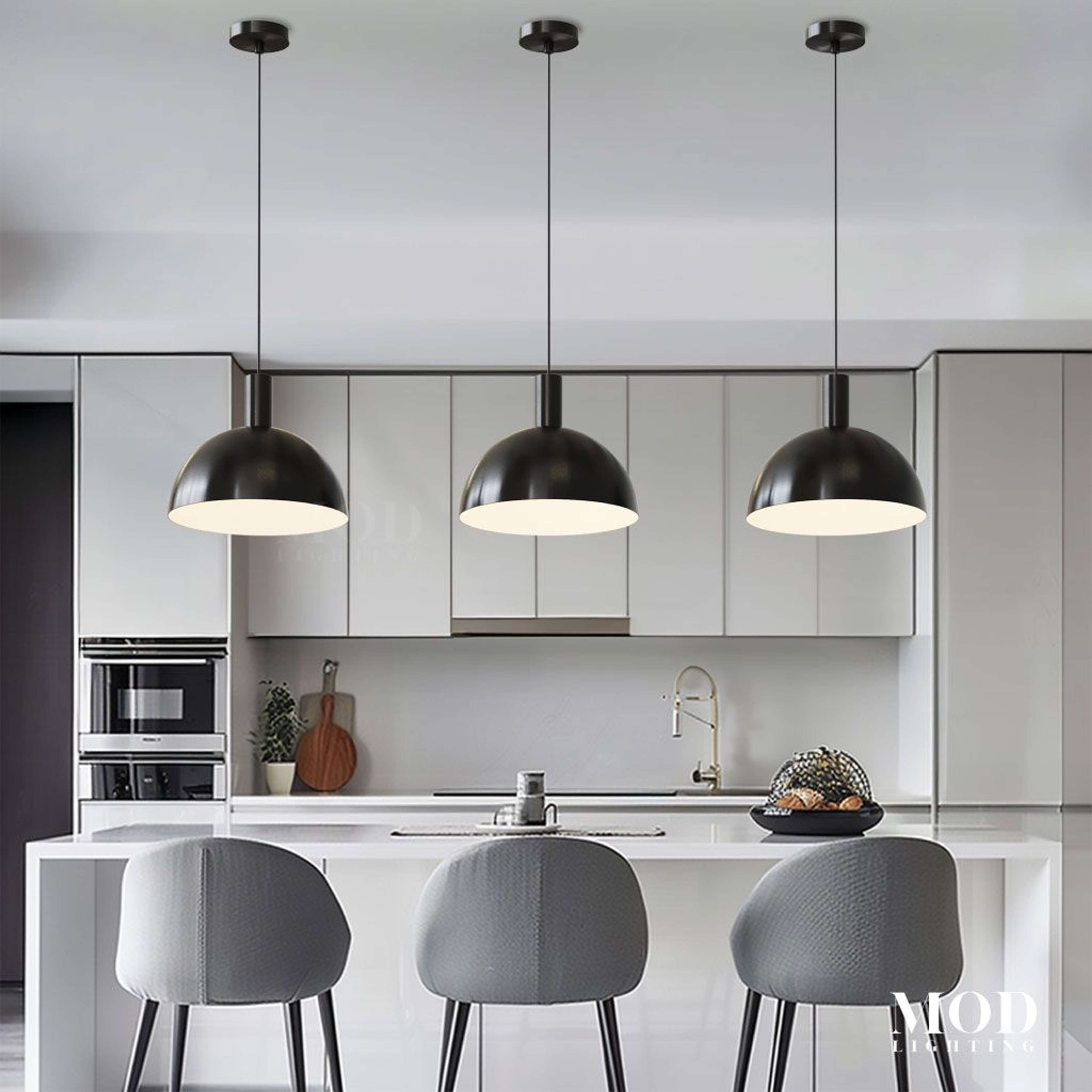 Kinsley pendant trio in matte black, dome shades suspended over a white kitchen island with grey bar stools