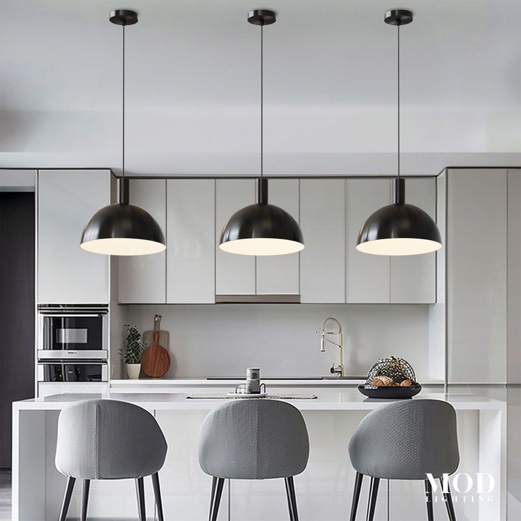 Kinsley pendant trio in matte black, dome shades suspended over a white kitchen island with grey bar stools