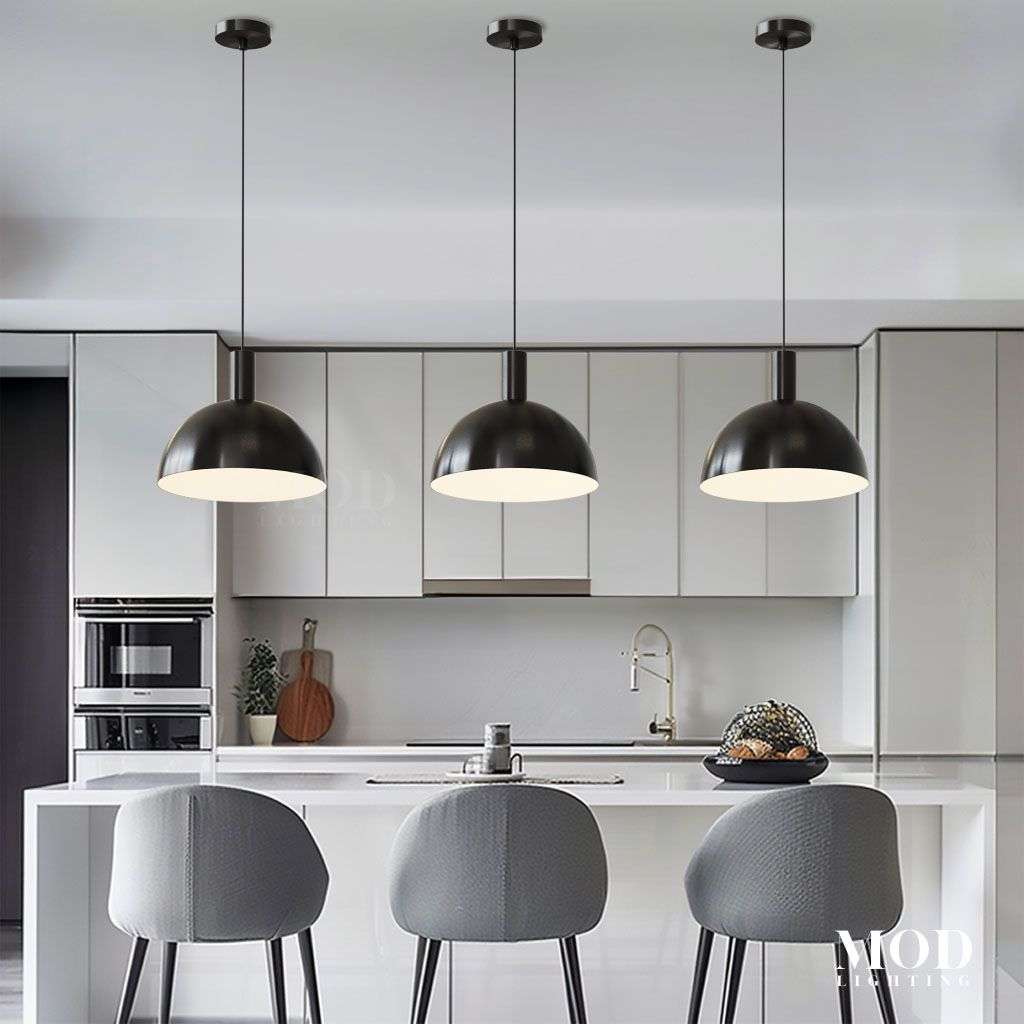 Kinsley pendant trio in matte black, dome shades suspended over a white kitchen island with grey bar stools