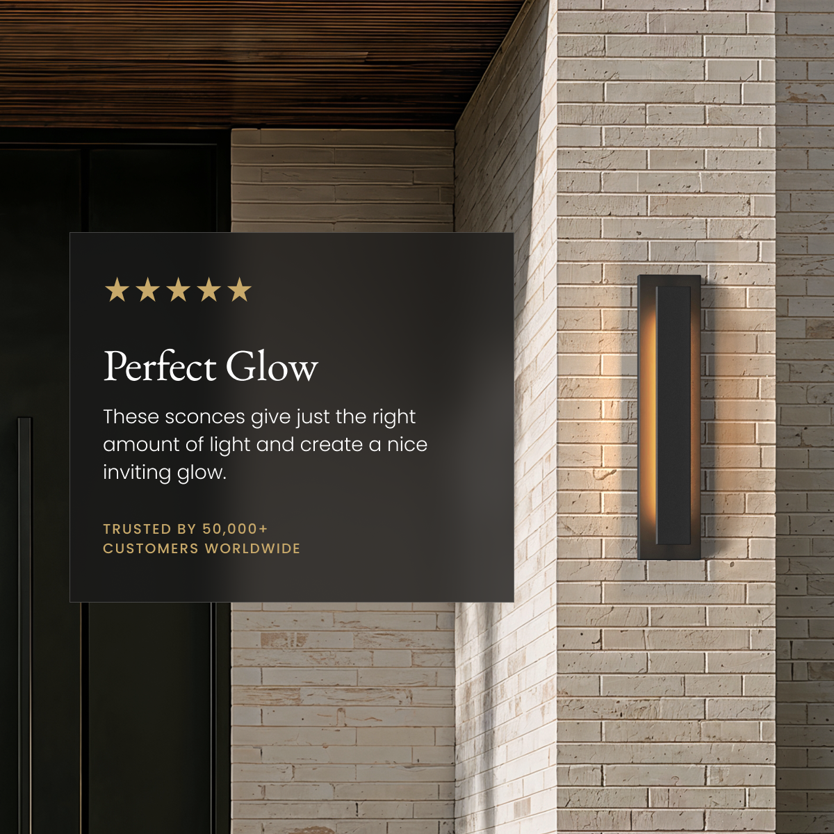 Vetra black outdoor sconce, slim vertical LED bar glowing on a stone-brick facade beside a review card