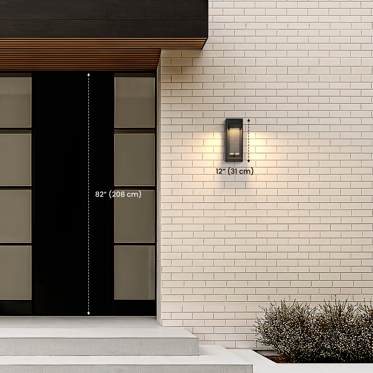 Aura black outdoor sconce by an entry door, dimension diagram noting 12 in / 31 cm height