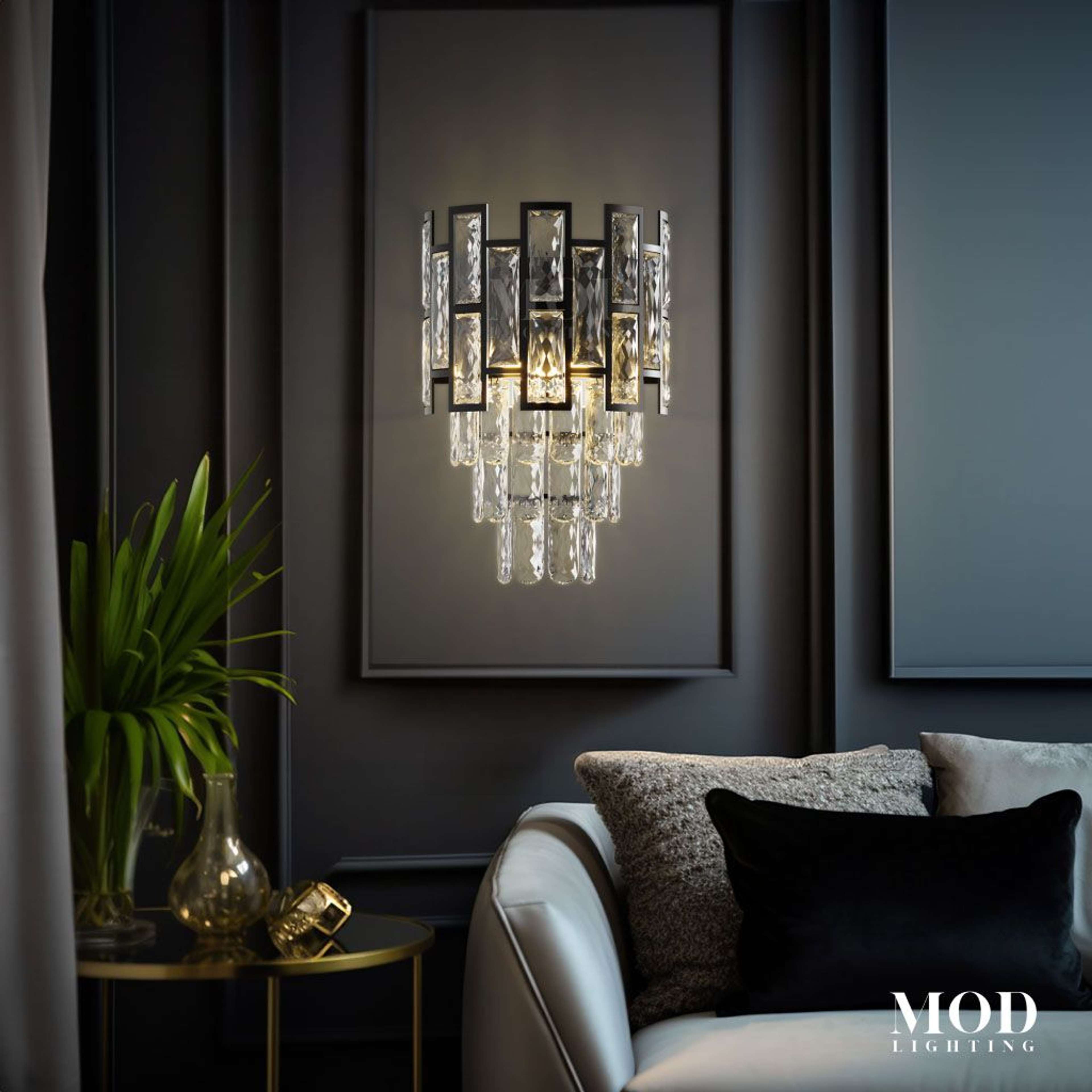 Raven Sconce, black crystal-tiered wall sconce lit on a dark wall above a sofa