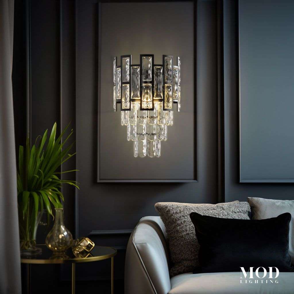 Raven Sconce, black crystal-tiered wall sconce lit on a dark wall above a sofa