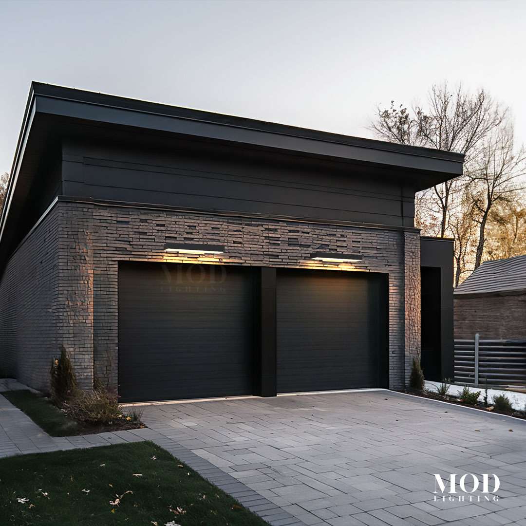 Brook black LED wall lights, two wide horizontal bars glowing above garage doors on a stone modern facade