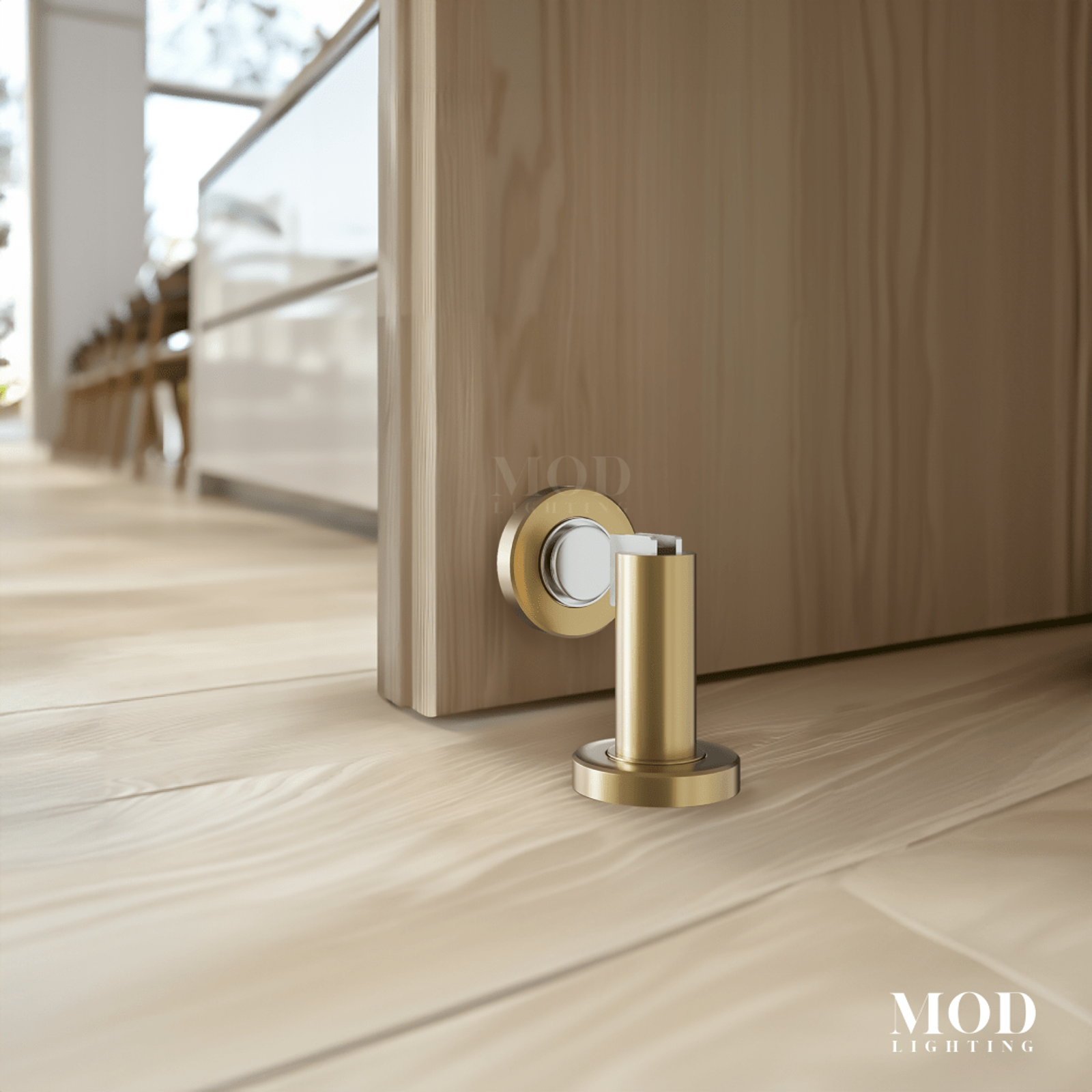 Modern Door Stop in brushed gold, floor-mounted magnetic post against a wood door on pale oak flooring