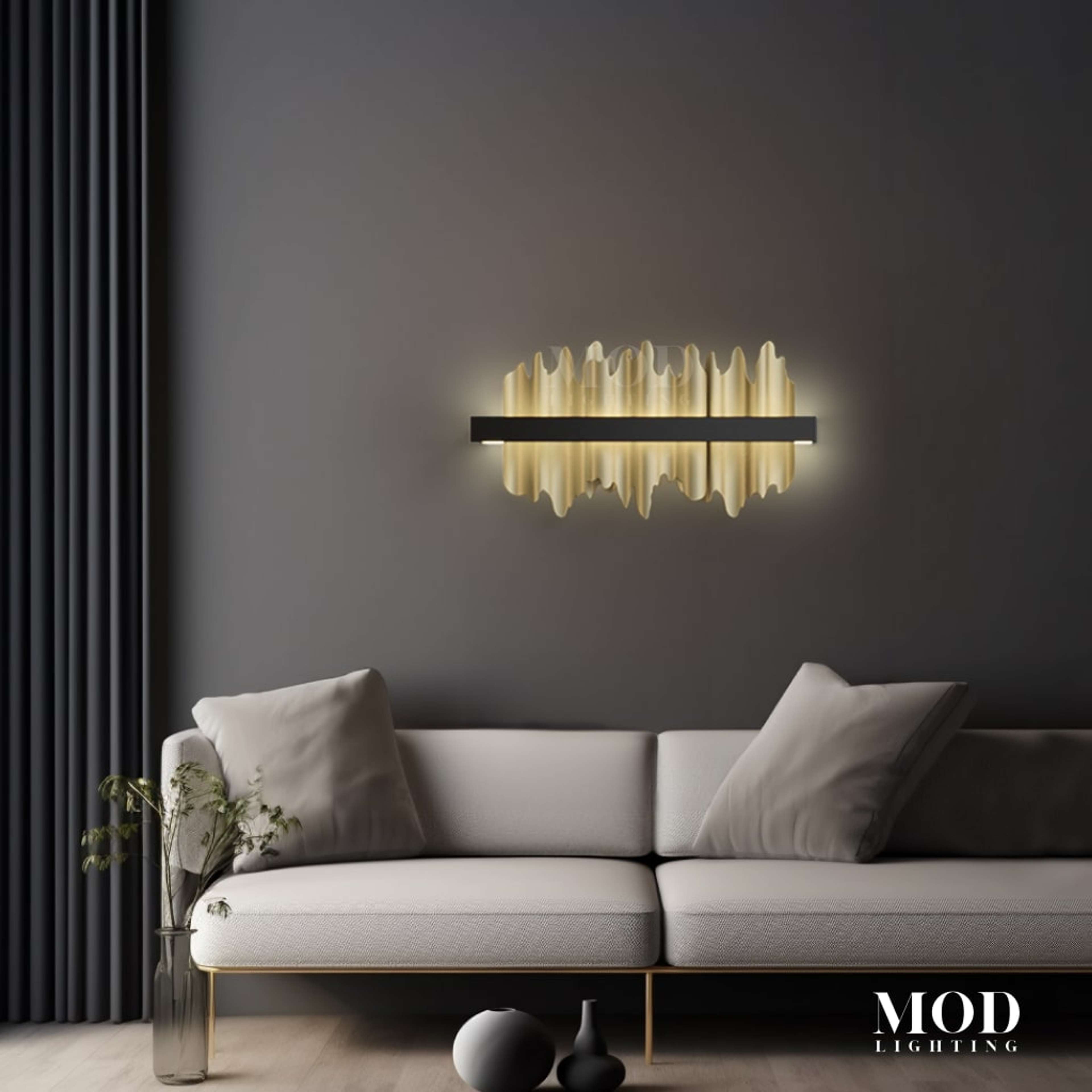 Aurelius gold-and-black wall sconce, jagged icicle-like glass border, glowing on a dark living room wall above a sofa