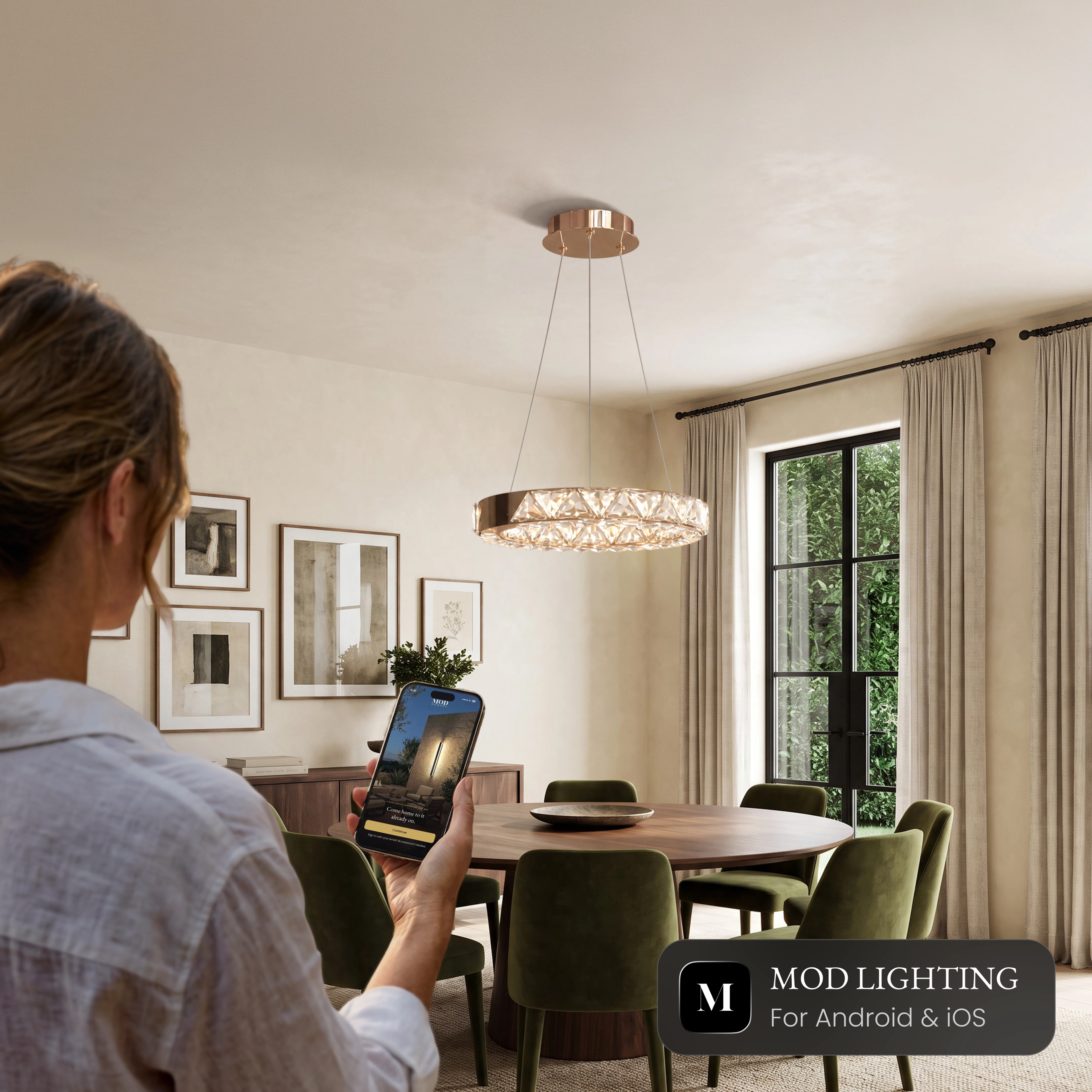 Jana Smart crystal ring chandelier over a dining table, controlled from the MOD LIGHTING app on a phone