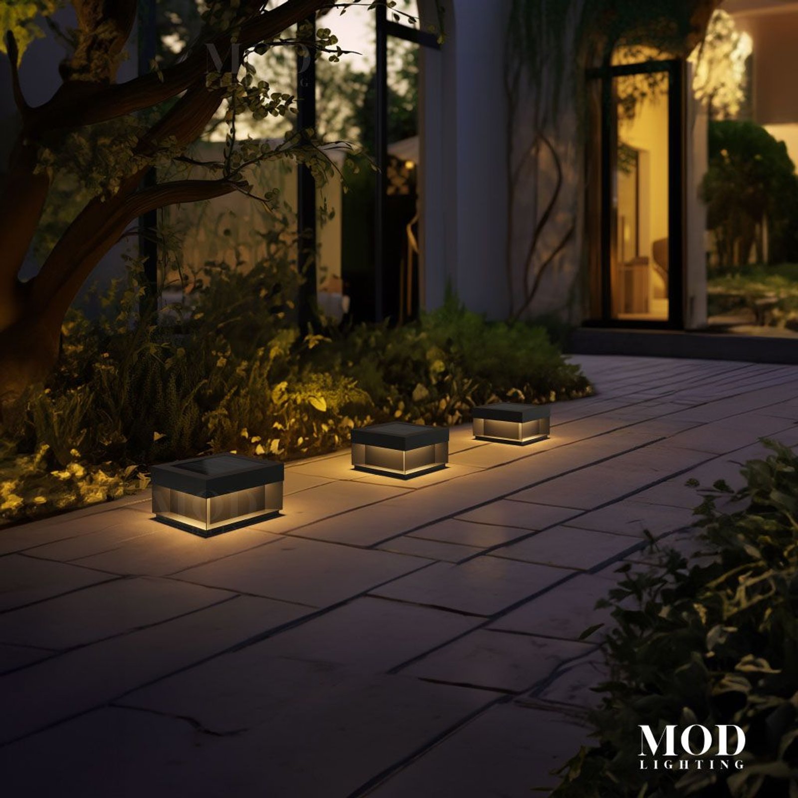 Chaz three warm-glowing solar bollard path lights on a paved garden walkway at night