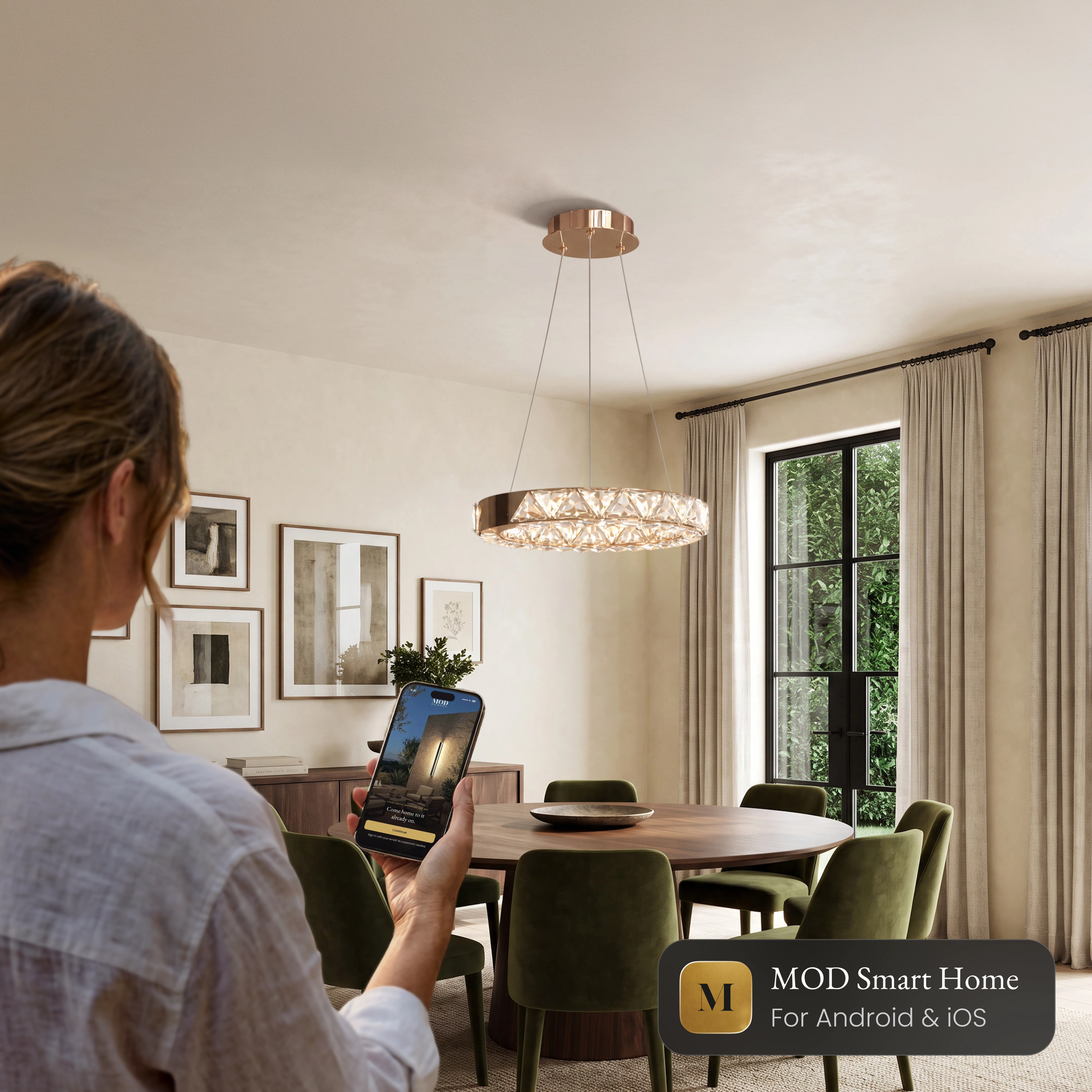 Jana Smart crystal ring chandelier over a dining table, controlled from the MOD Smart Home app on a phone