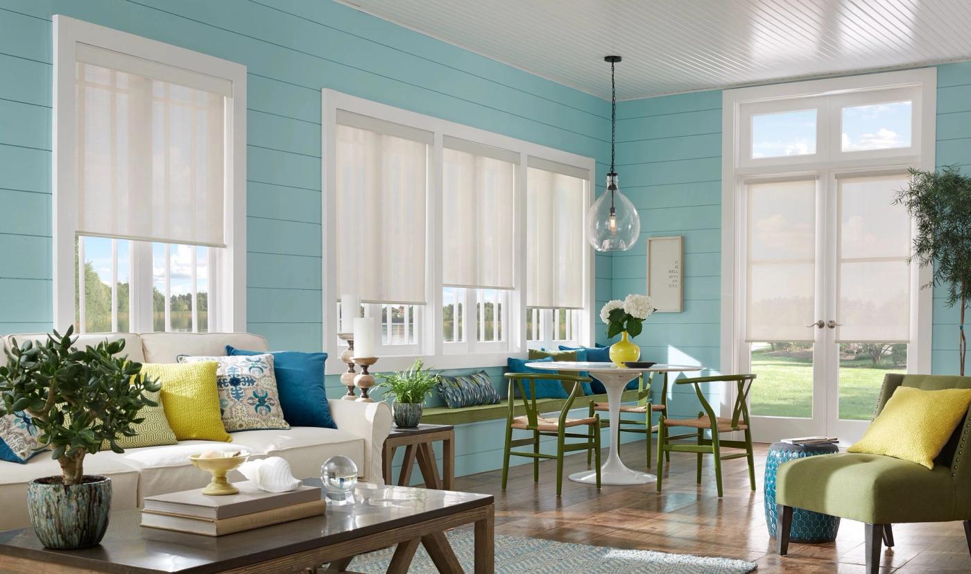 Cordless roller shades with motorized lift and remote control in sunroom