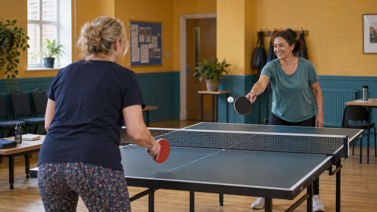 Two women enjoy a relaxed game of table tennis at a community centre.