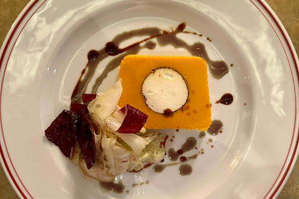 Ein Teller mit einer Terrine aus Kürbis mit einem Kern von Ziegenfrischkäse 