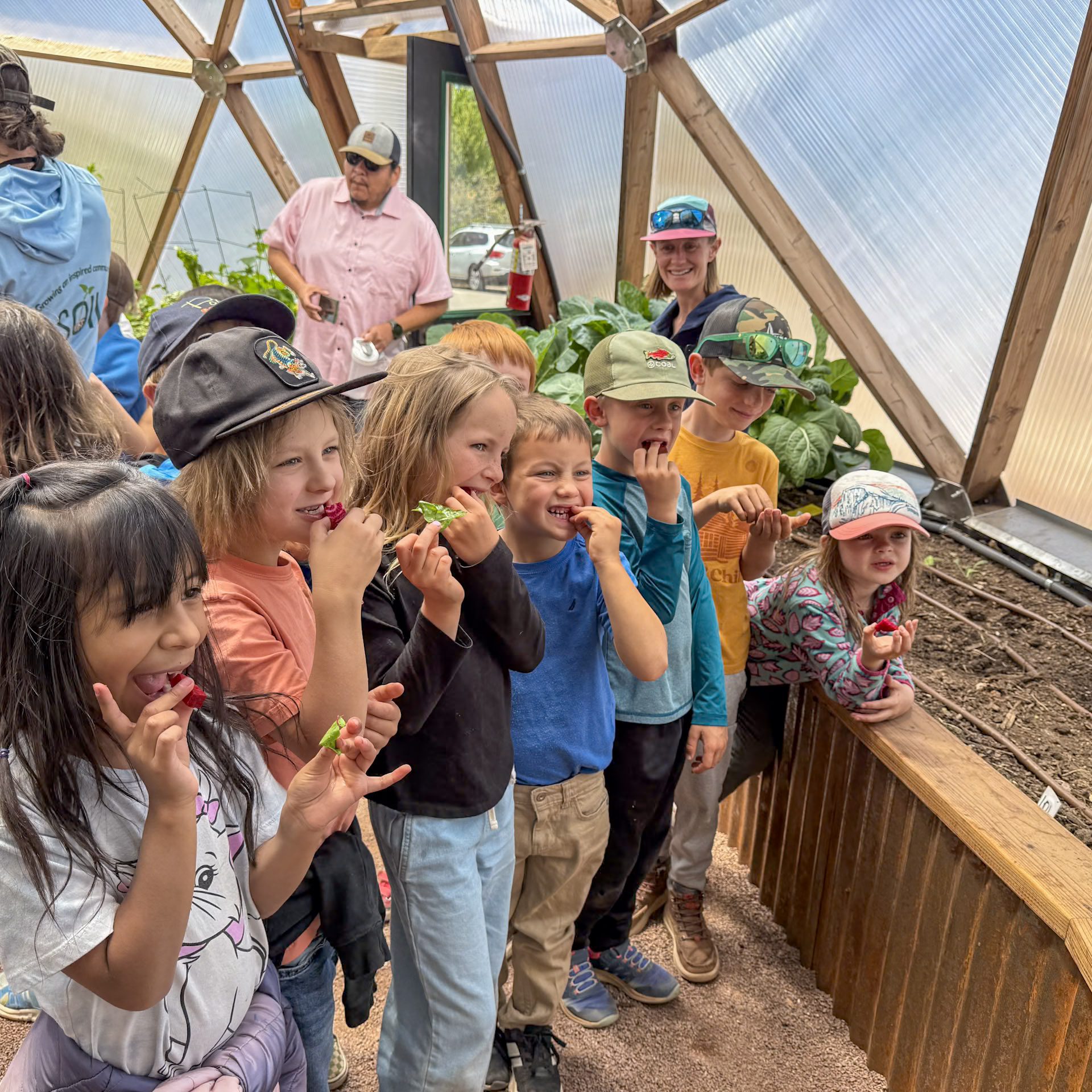 Seven young kids trying fresh beet root in a Growing Dome smiling for the camera