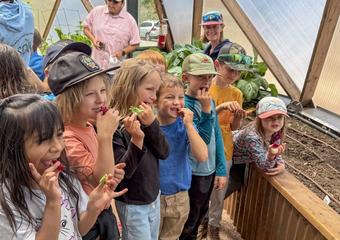 Seven young kids trying fresh beet root in a Growing Dome smiling for the camera